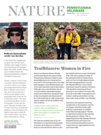 Three women wearing yellow fire gear pose together during a controlled burn.