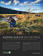 The cover of a newsletter shows a man kneeling in a field to adjust a camera.