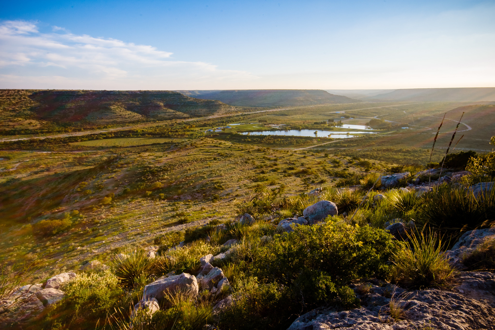 Sweeping view of green valleys, mesas and ponds.