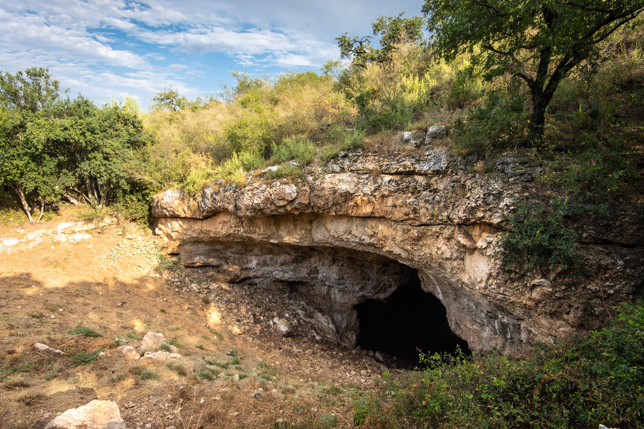 Rocky, limestone cave with a deep, black opening.