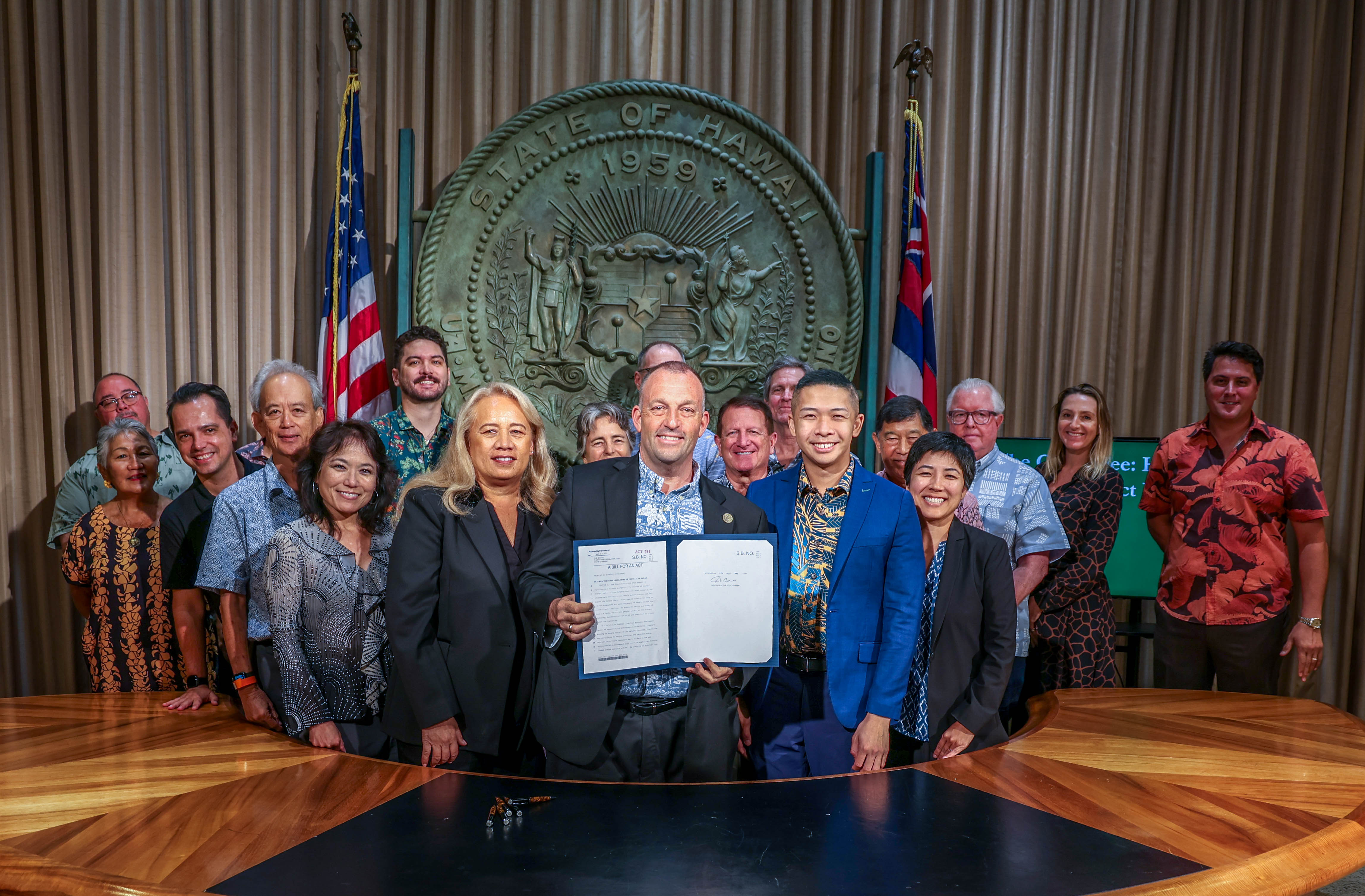Several people stand together for a group photo at the signing of Hawaiʻi’s Green Fee.