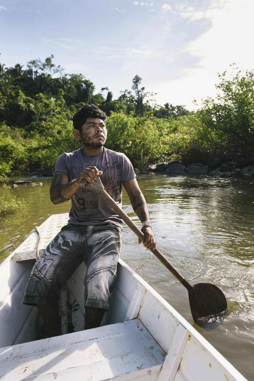 a young man in a paddle boat on a river.