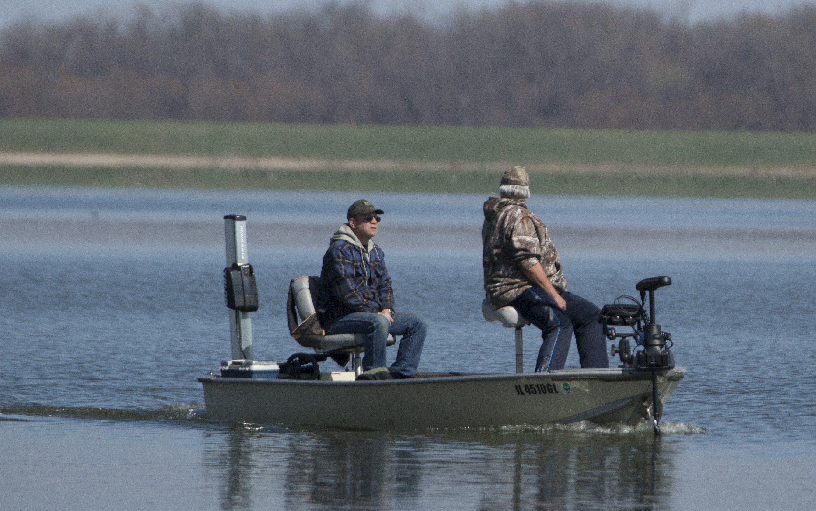 Two people on a fishing boat on the water. 