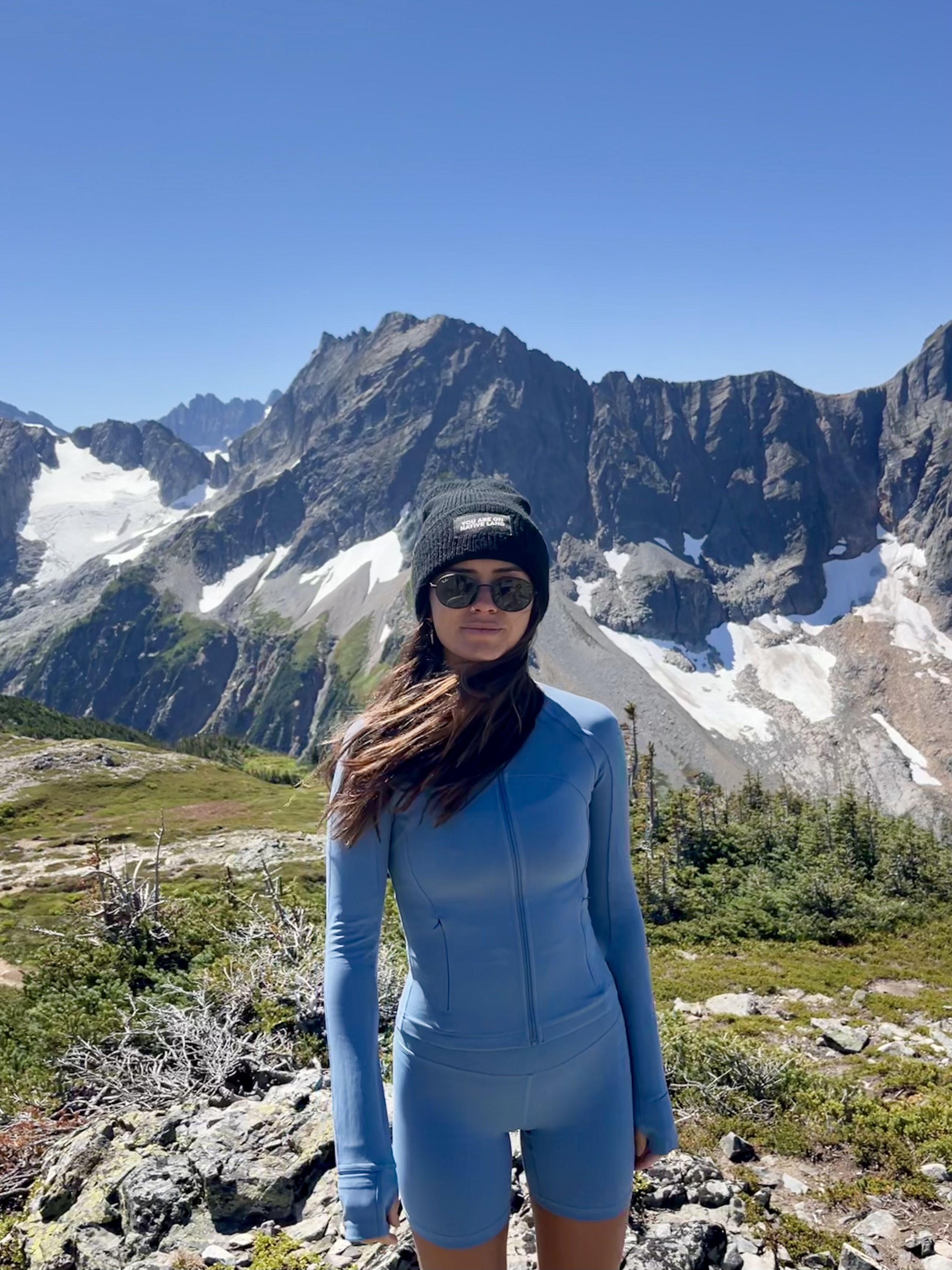 Izabella Ruffino wears hiking clothes and stands in front of snowcapped mountains.