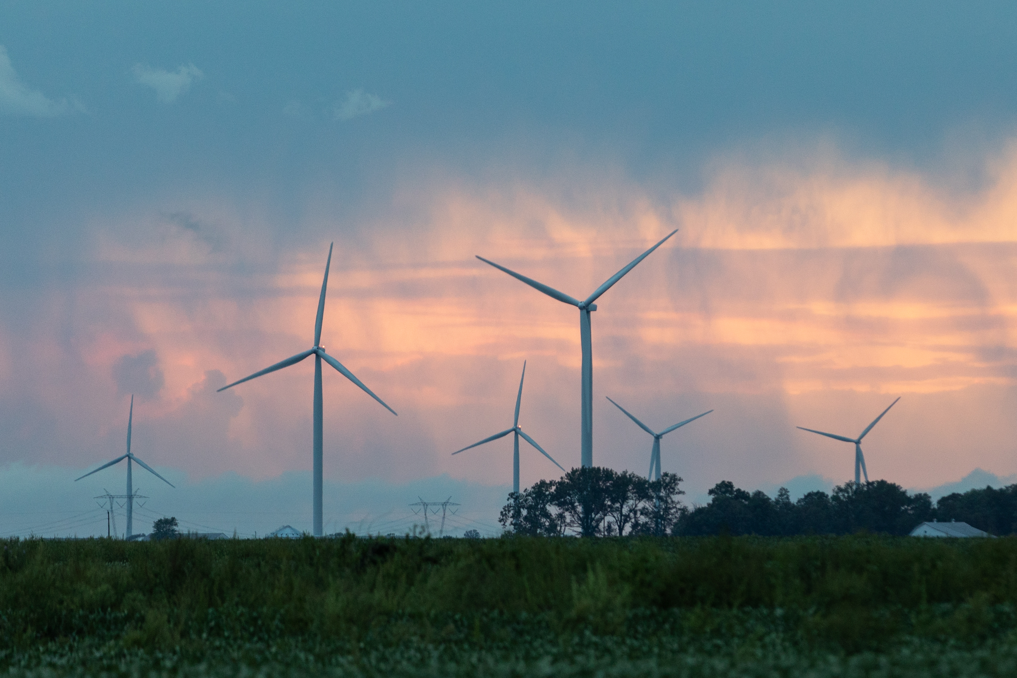 Windmills scattered across a Midwest landscape at sunset.