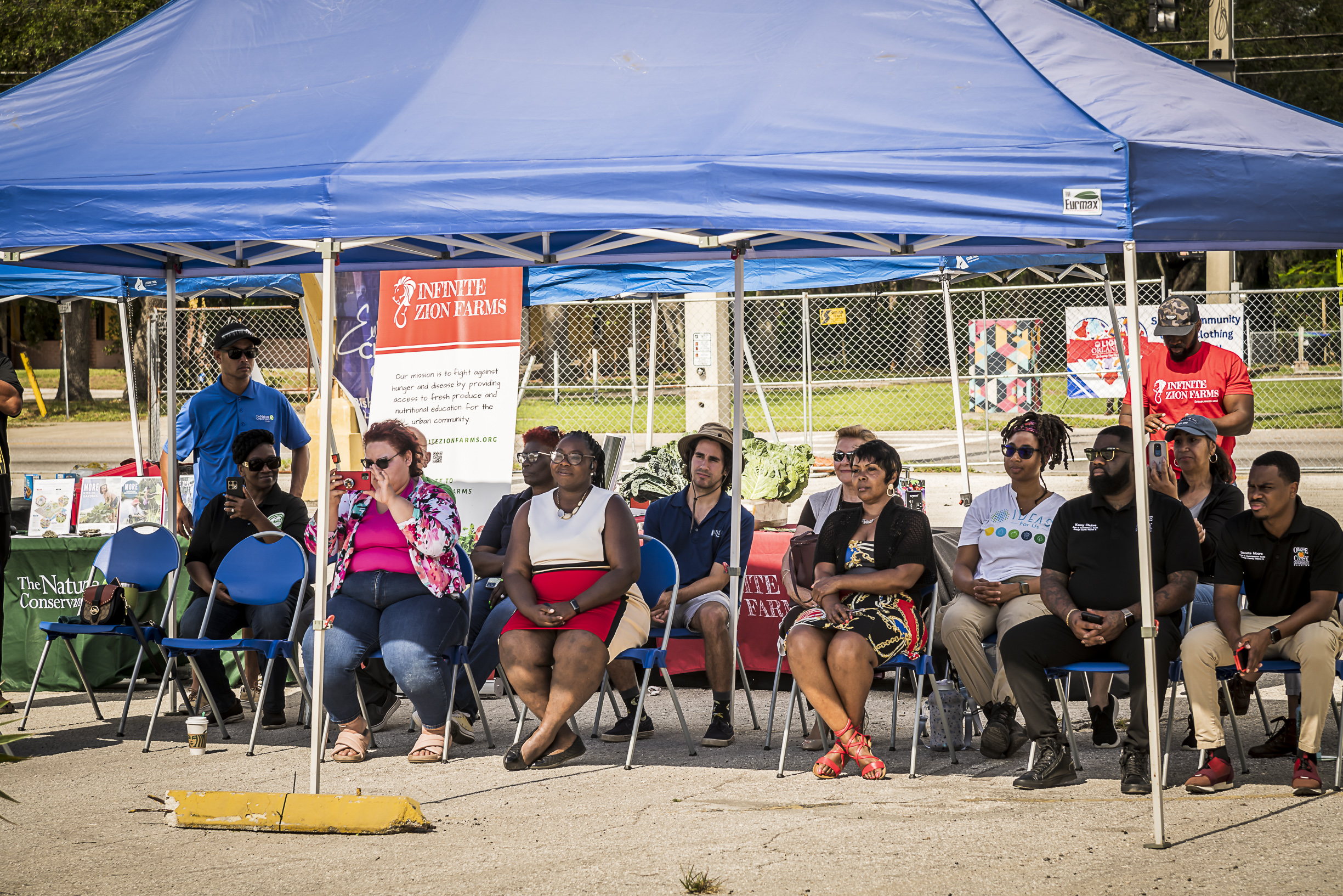 People sitting in chairs in the shade.