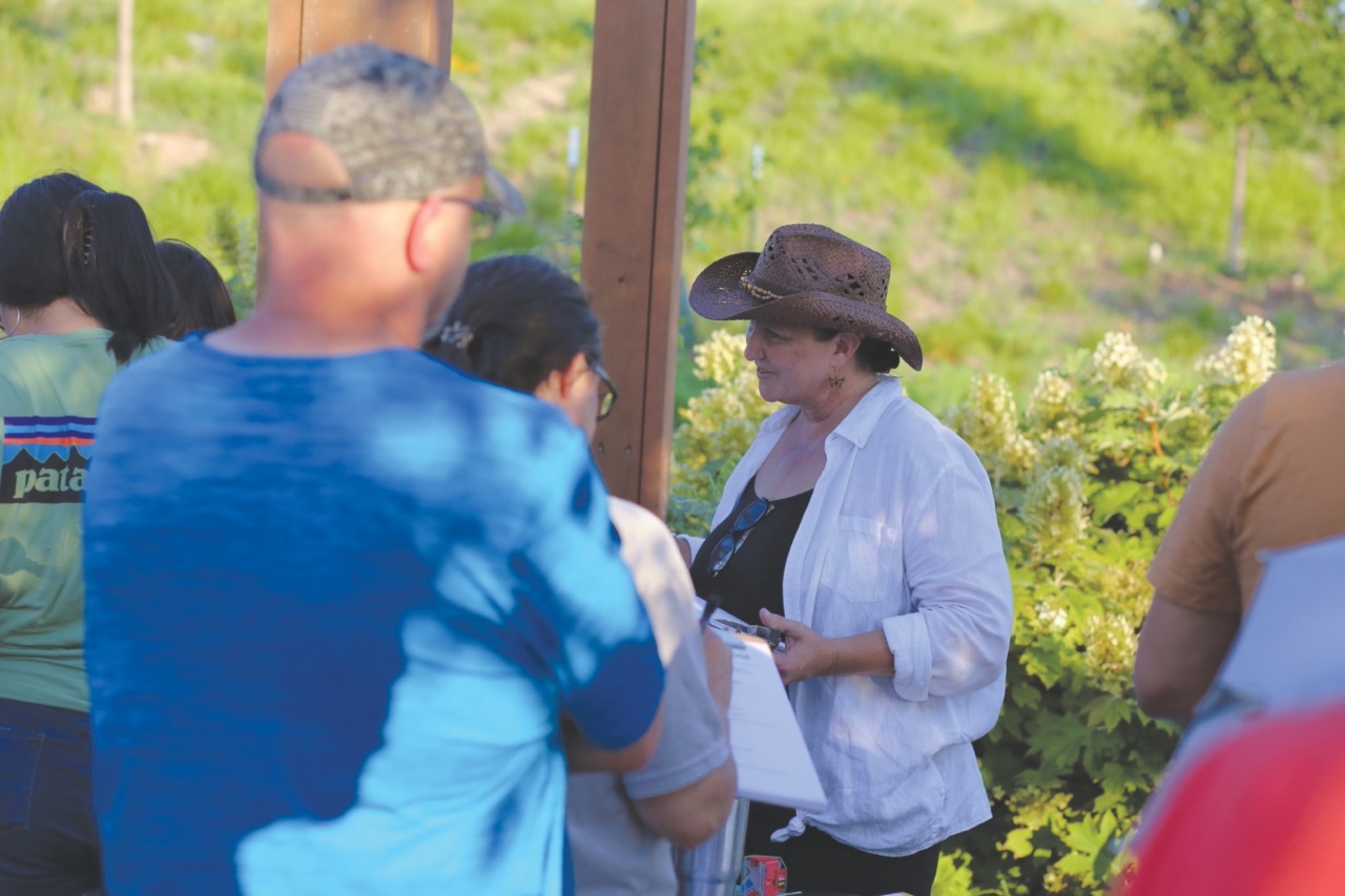Pollinator Outreach Coordinator Stephanie Jordan speaks with community members in a partially shaded garden.