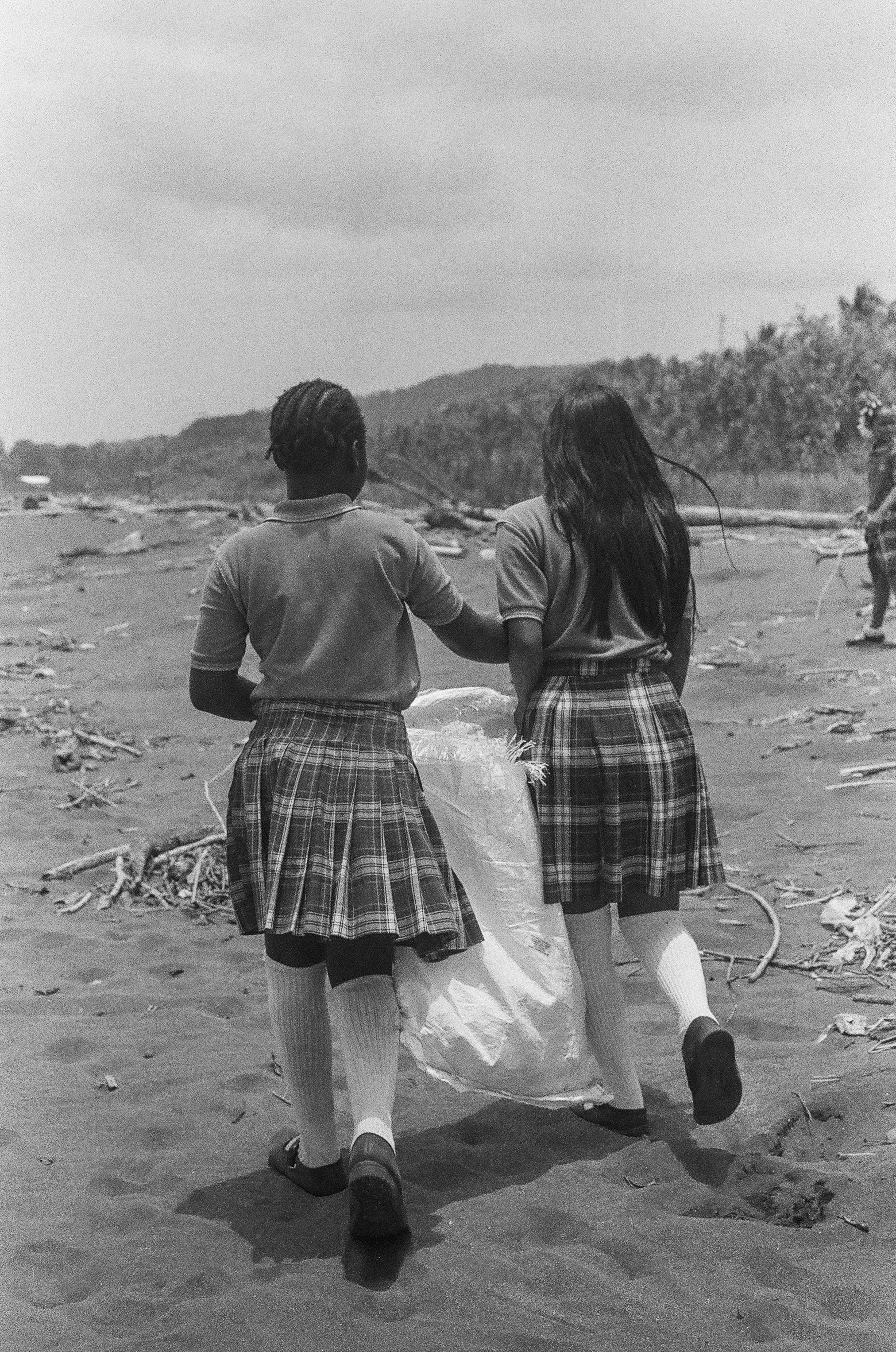 Two students collect trash during a beach cleanup. 