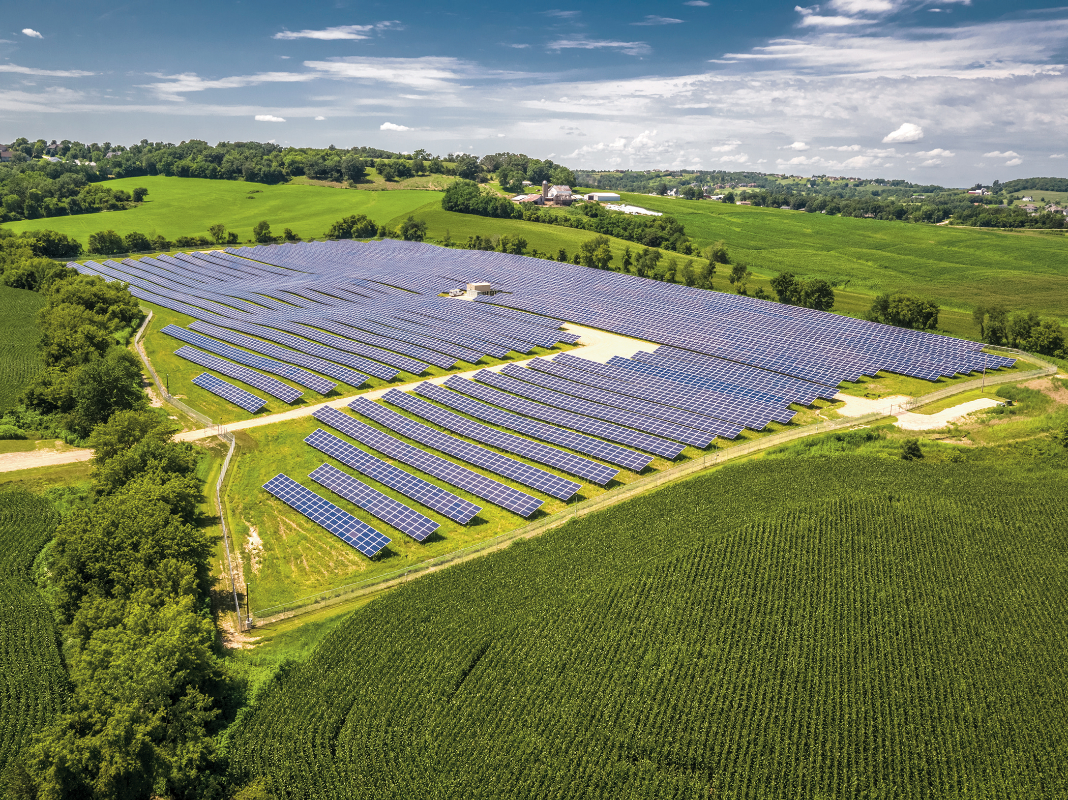 Aerial view of a solar farm surrounded by trees.