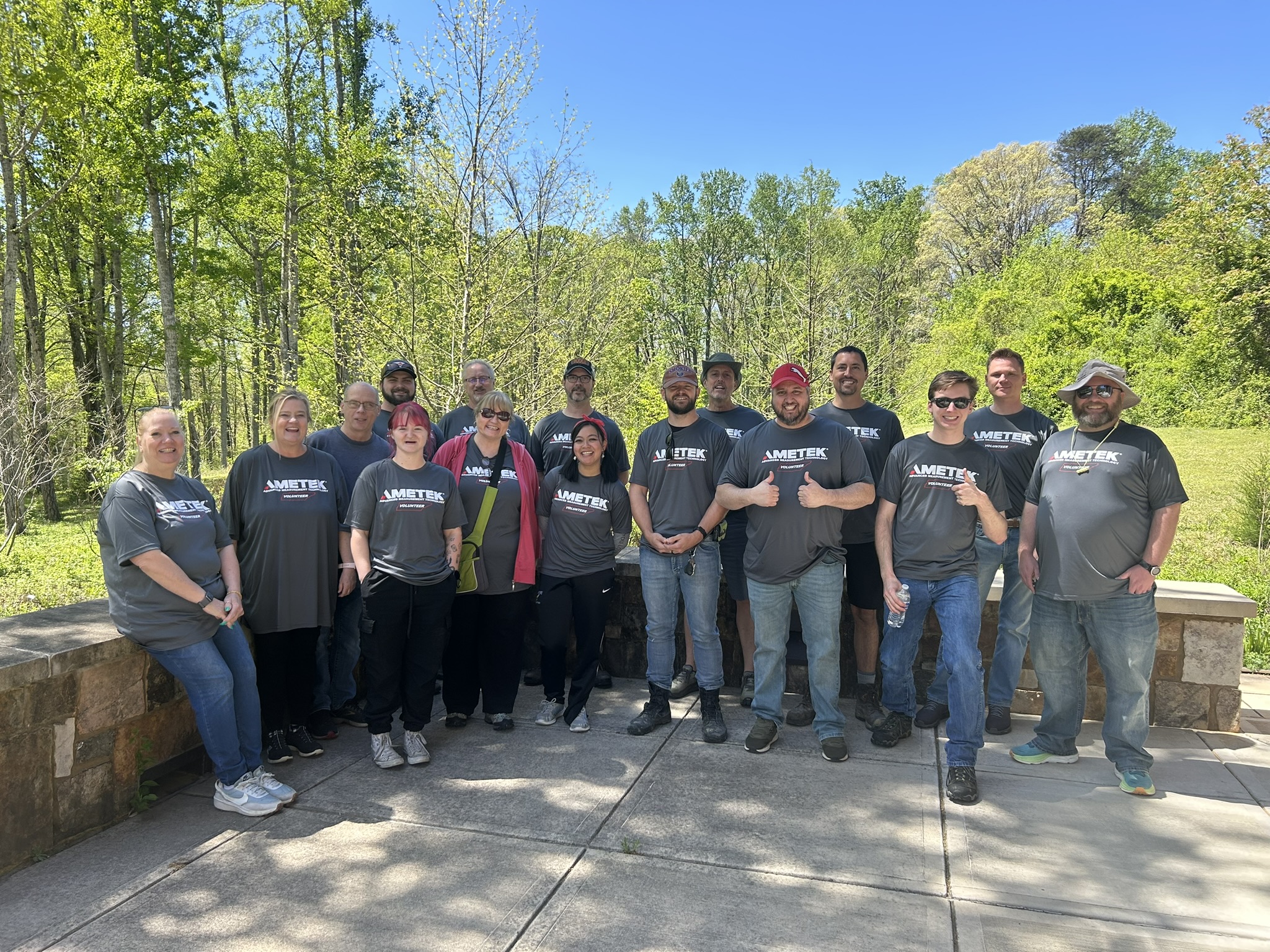 A group of people wearing AMETEK shirts smile at the camera. 