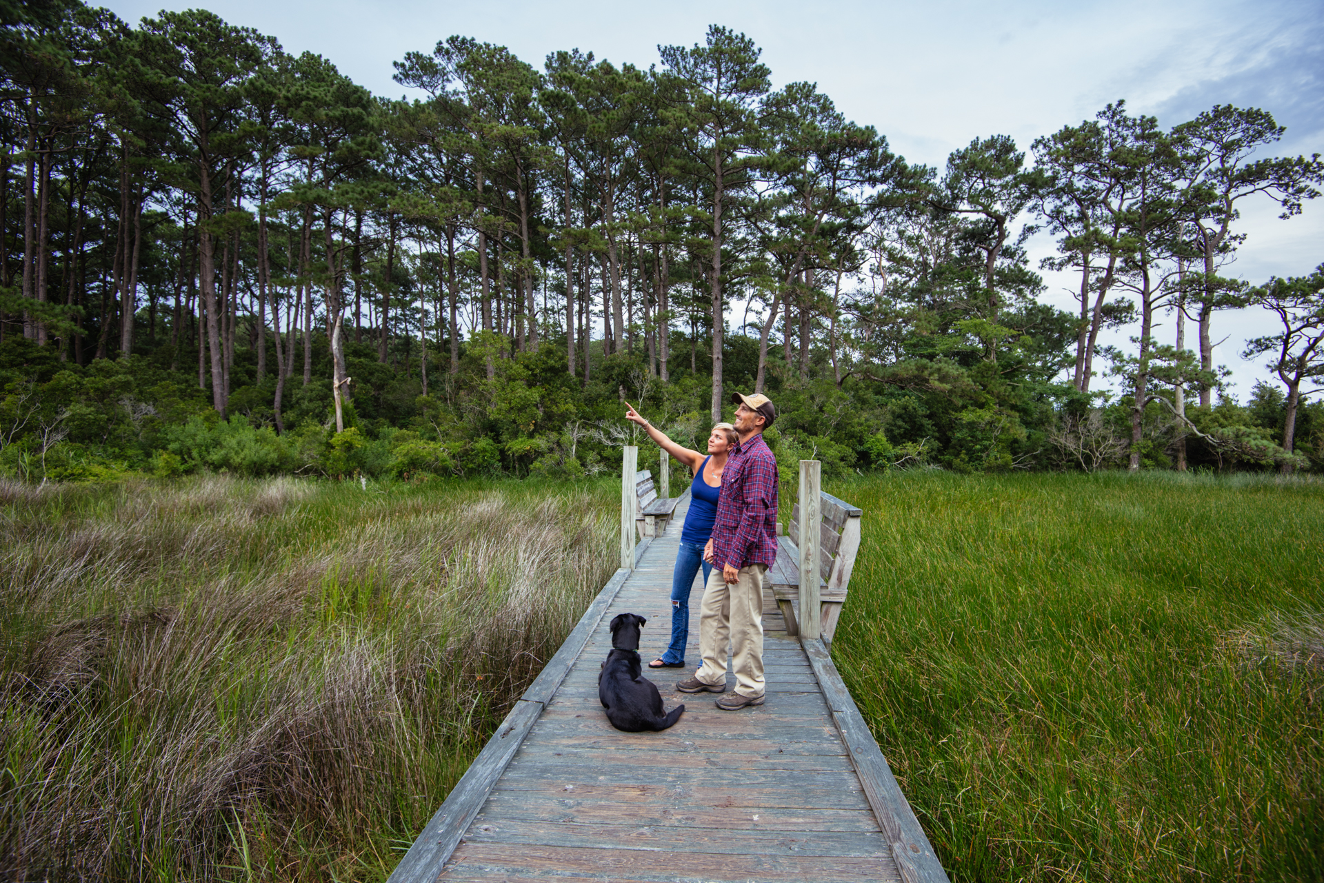 A family looks out at an open landscape from a boardwalk.