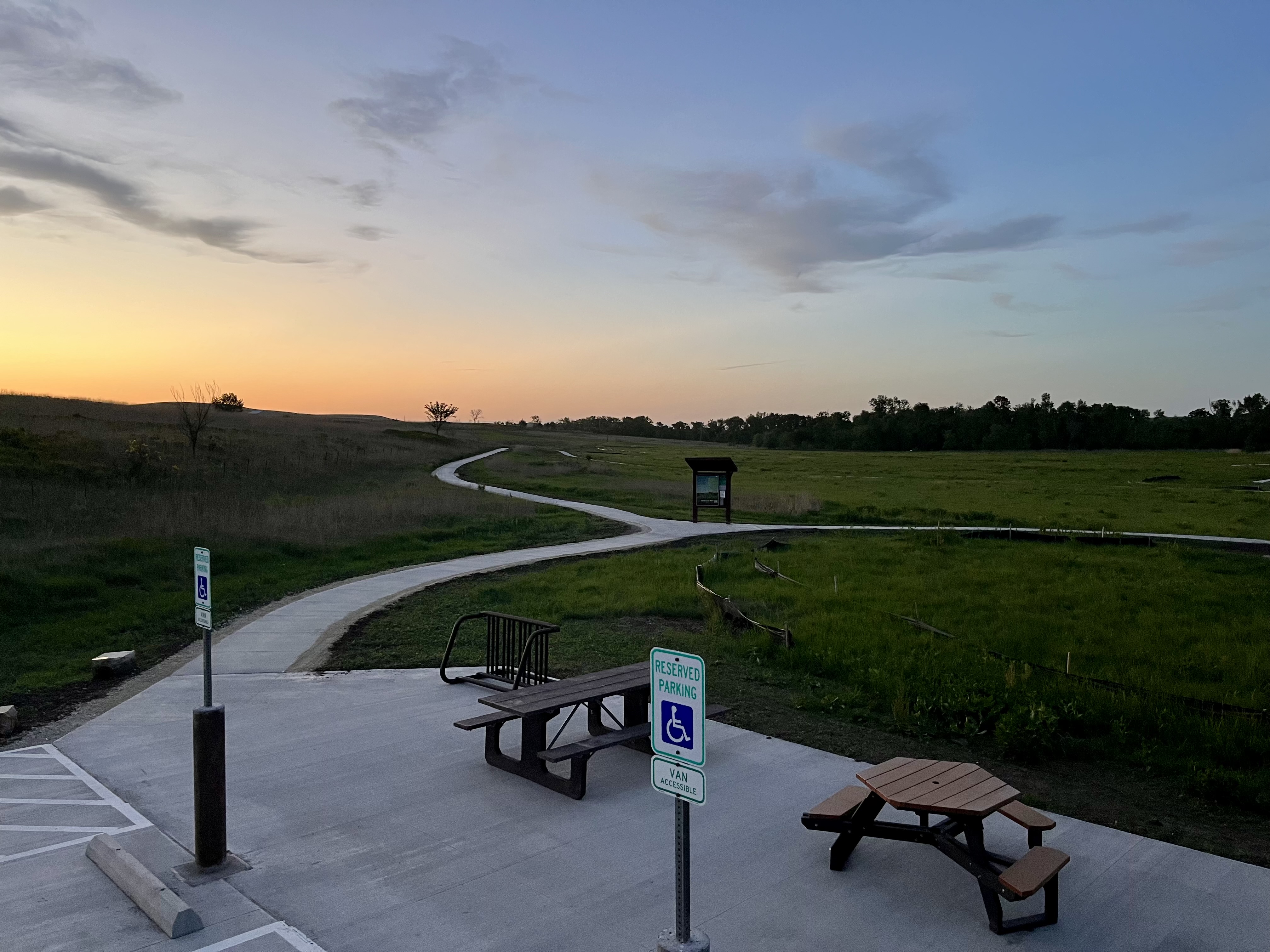 A cement path leads out into a vast, green landscape.