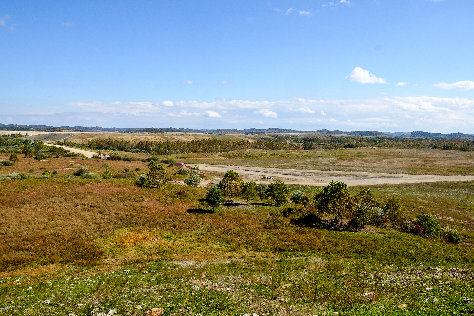 landscape with dirt road, trees and mine in distance
