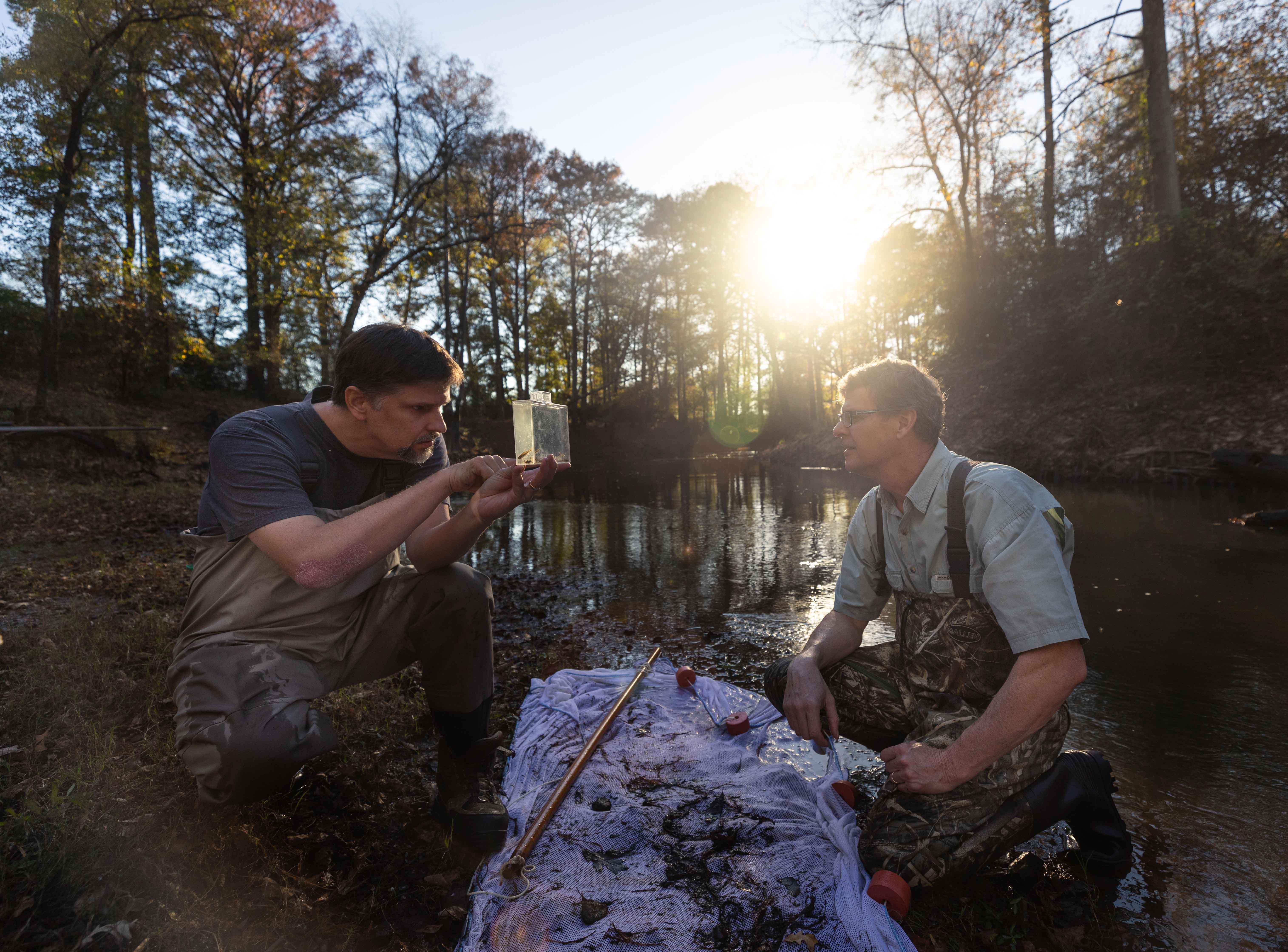 Two men examine a water sample pulled from a lake.