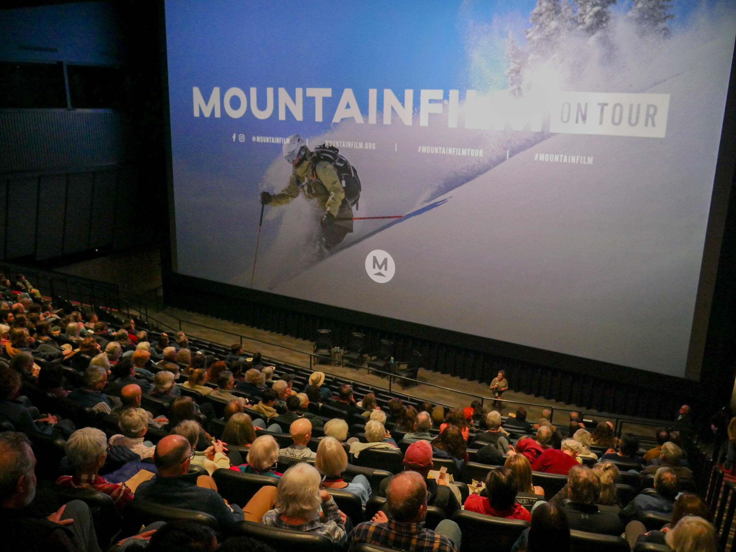 A theater full of people looking at a movie screen.