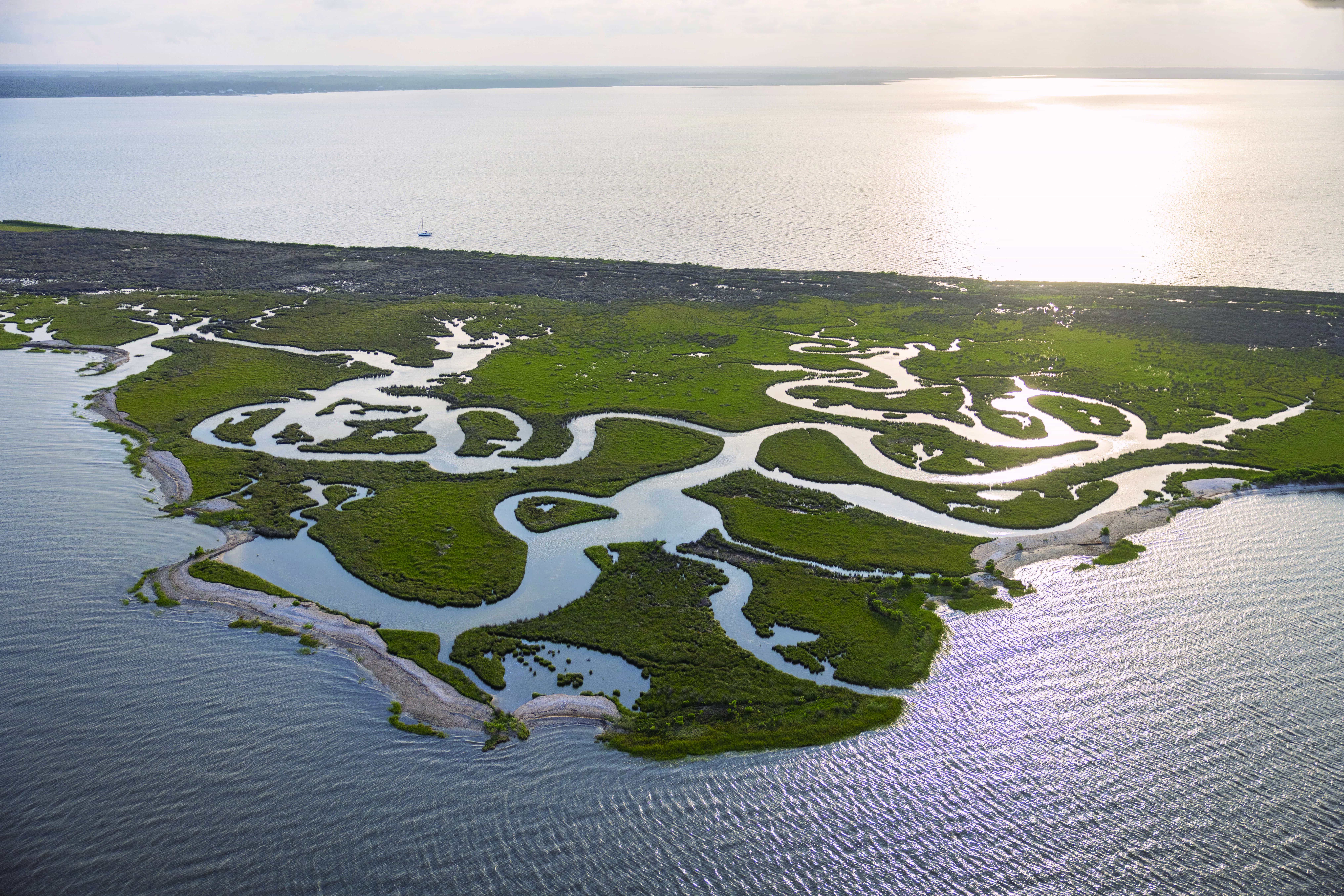 An aerial photograph features a small, grassy island divided by narrow waterways.