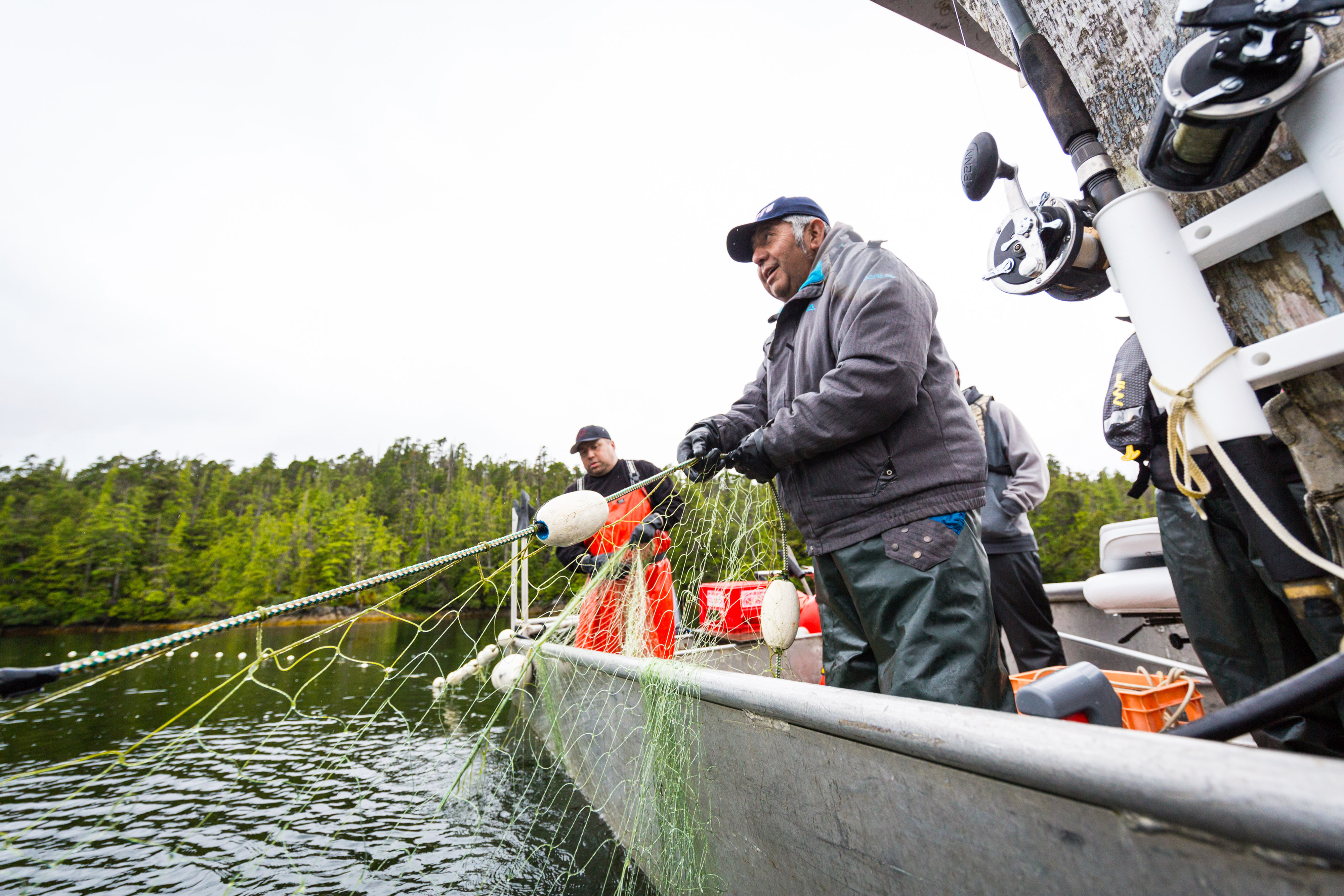 Two men stand in a small boat and haul in fishing nets.