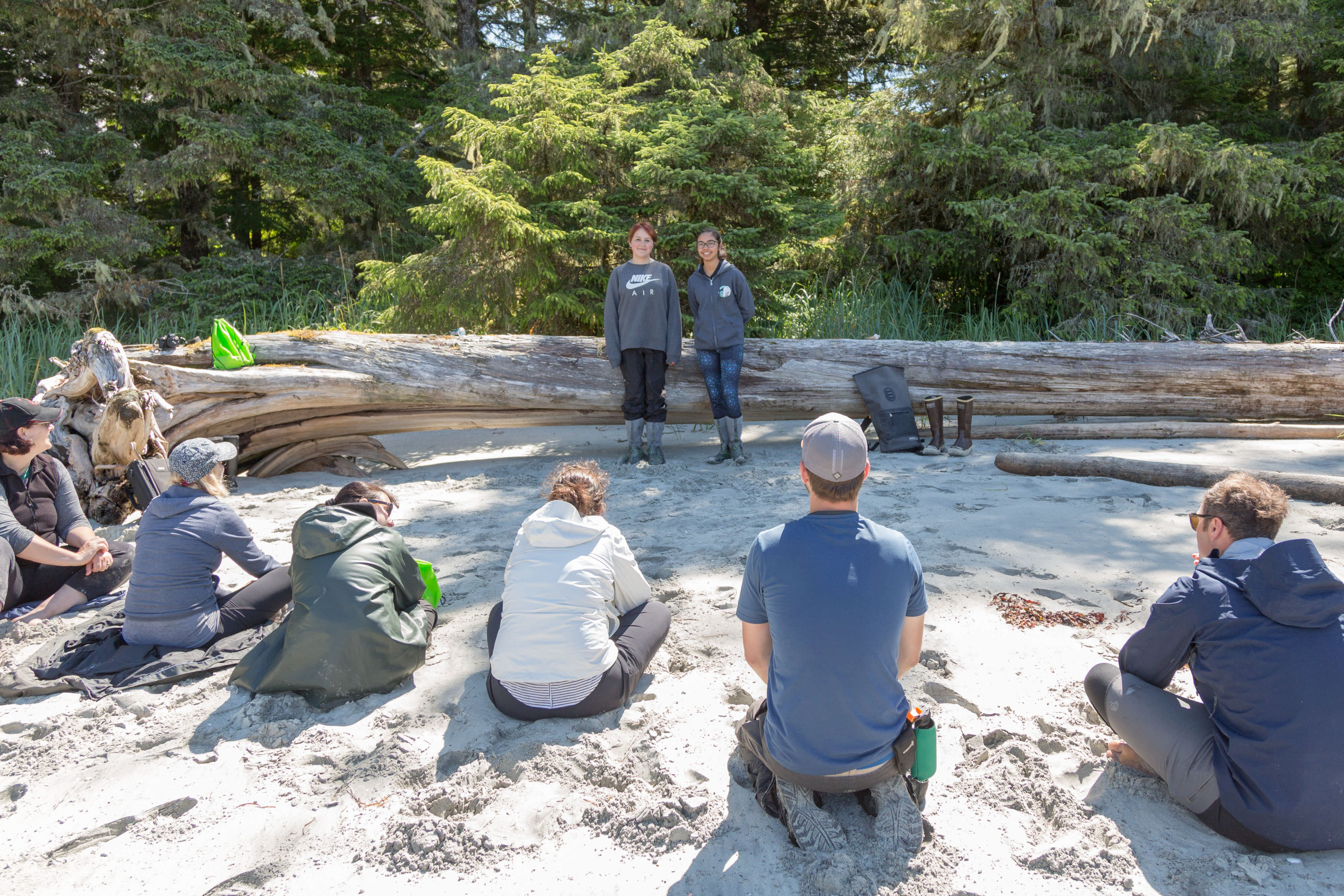 People sit on the ground listening to two people.