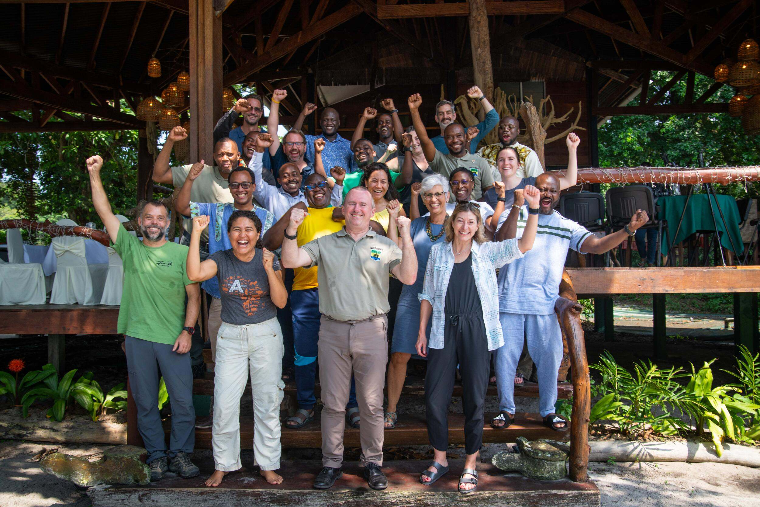 A large group of partners raise their arms up and cheer.