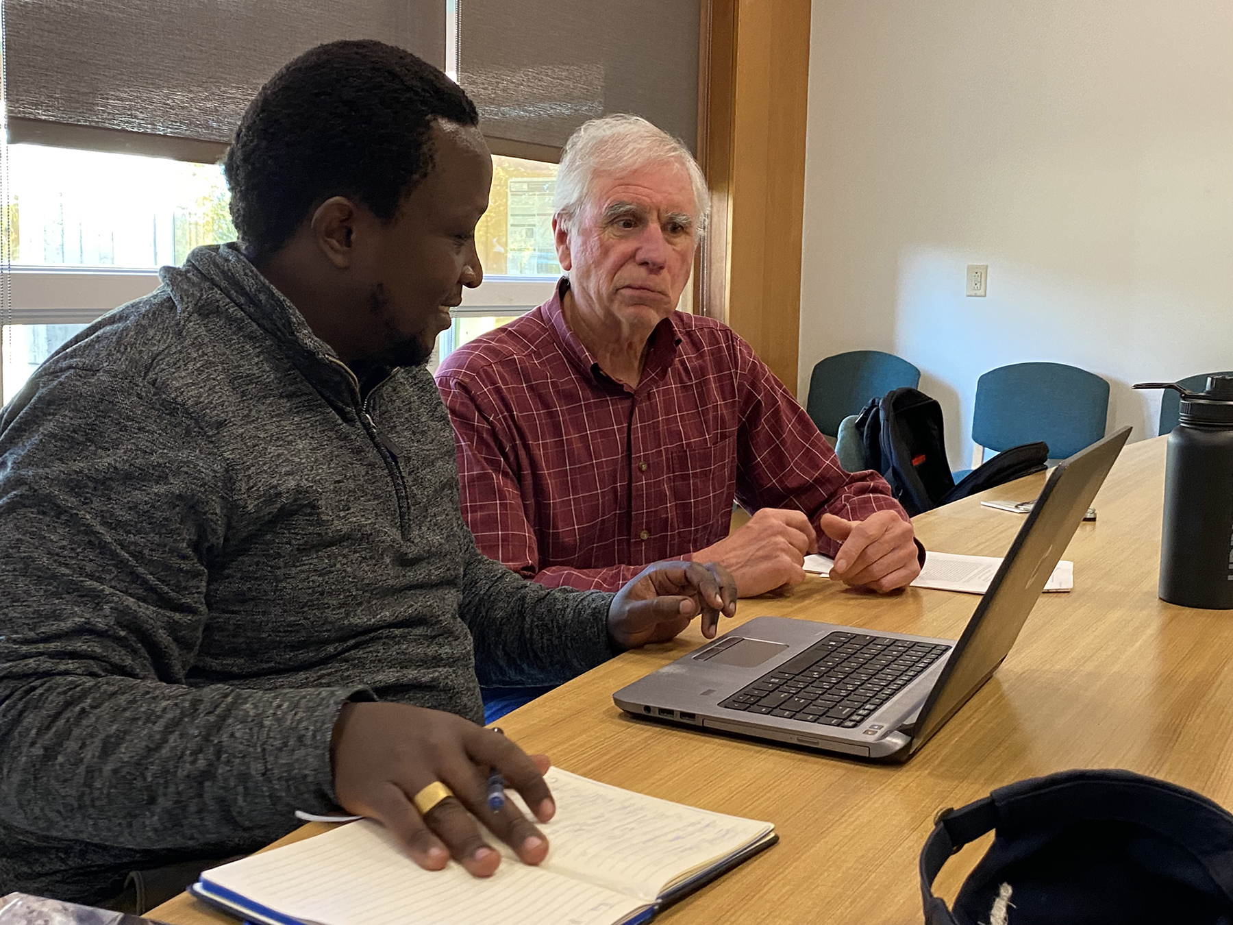 Two men work in front of a laptop computer.