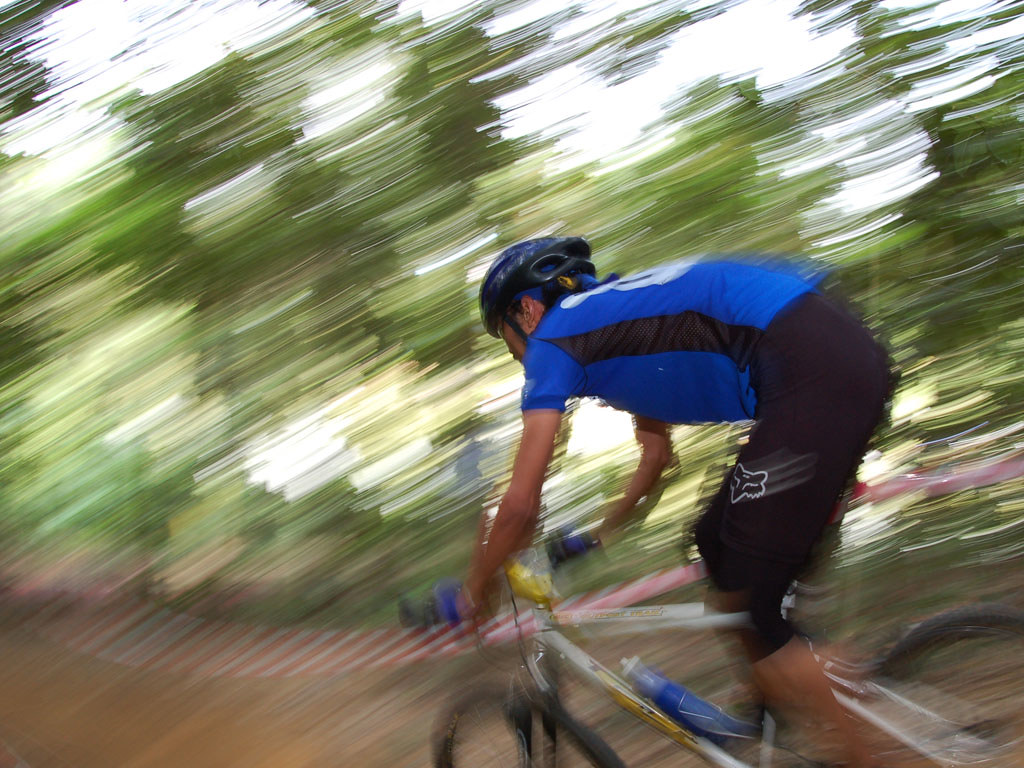 A person wearing a blue shirt bends over on a bike ride through woods.