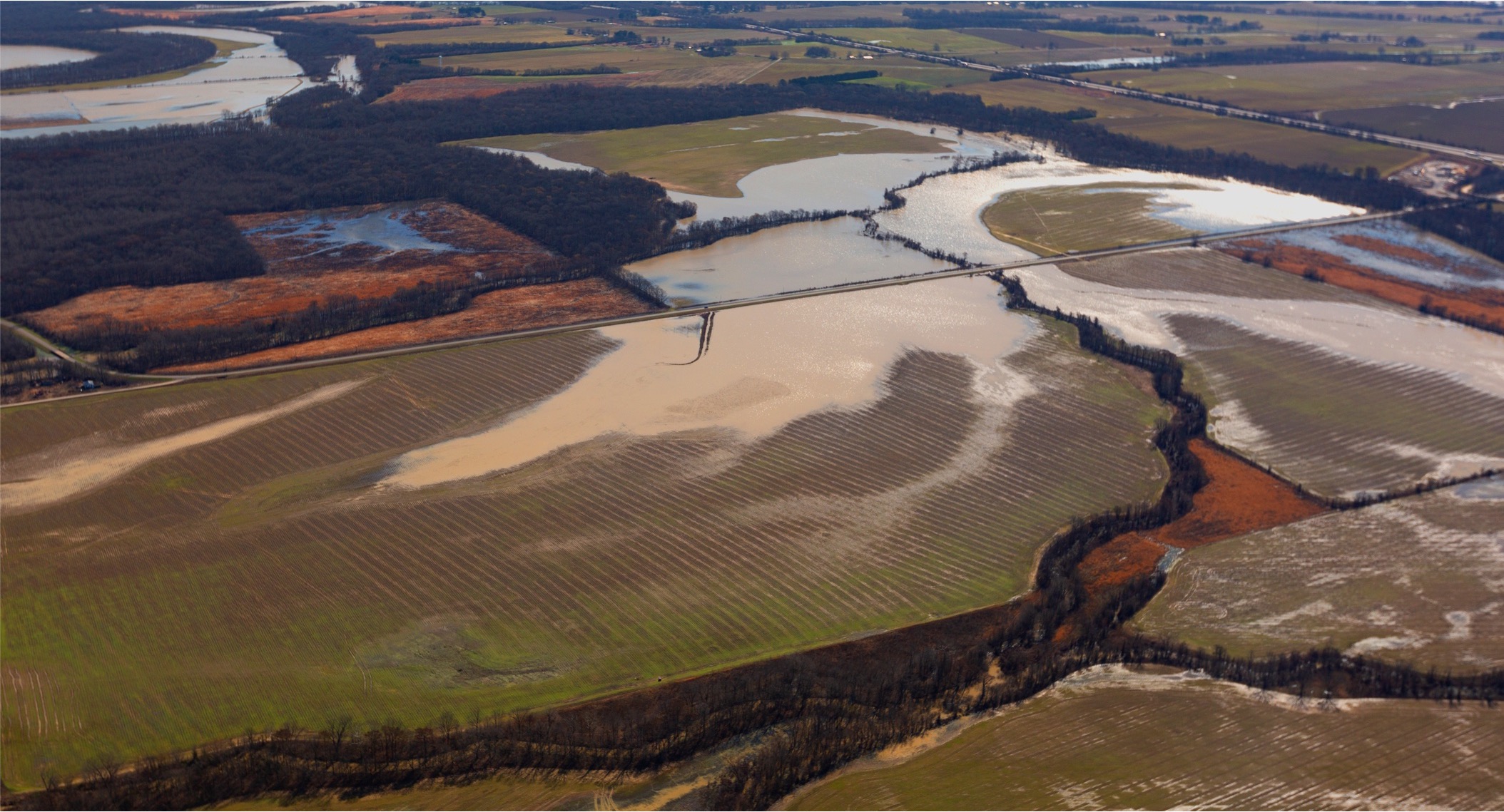 Aerial view of a large flooded area surrounded by forest.