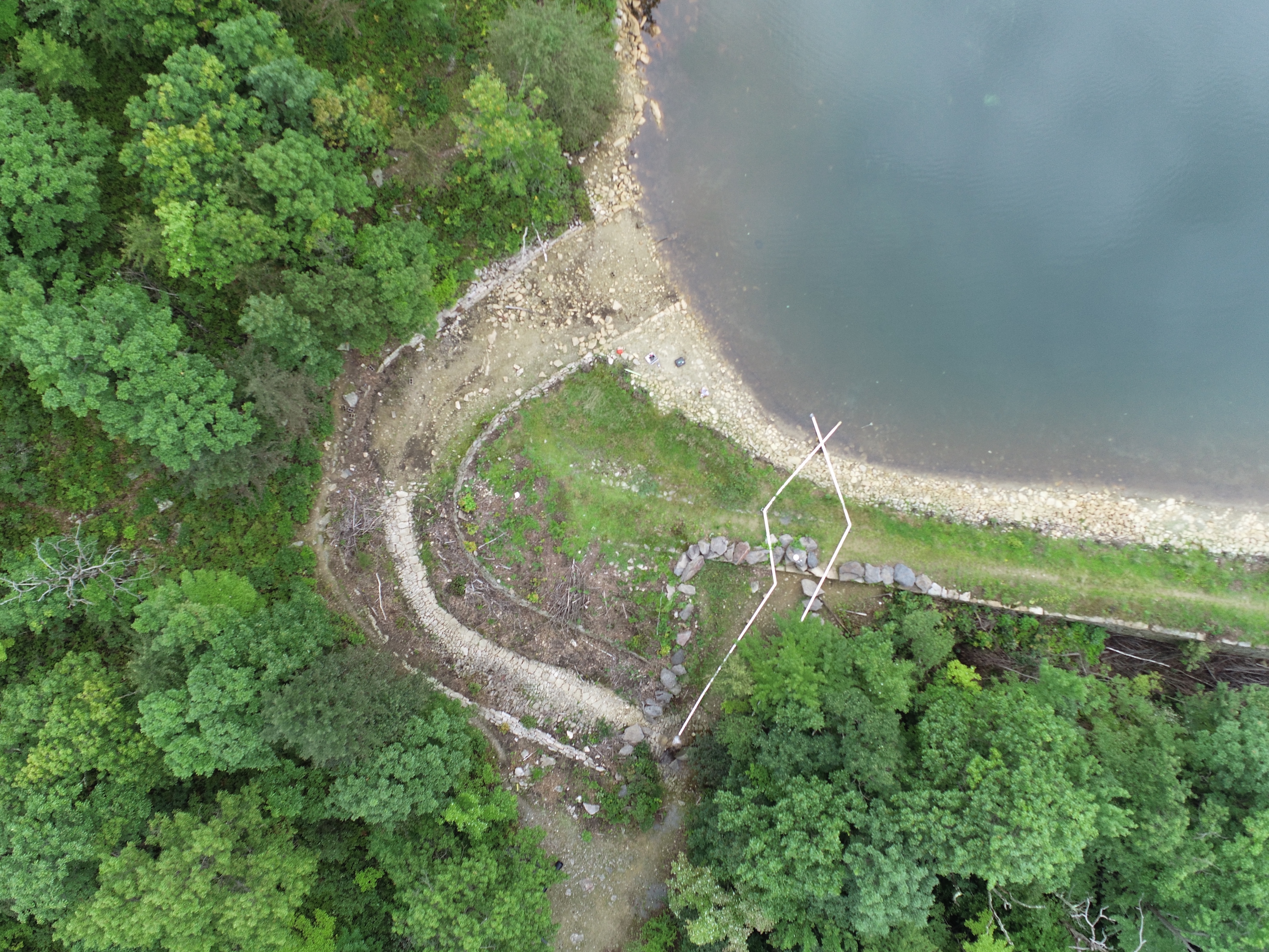 An aerial photo of a body of water against a tree line.