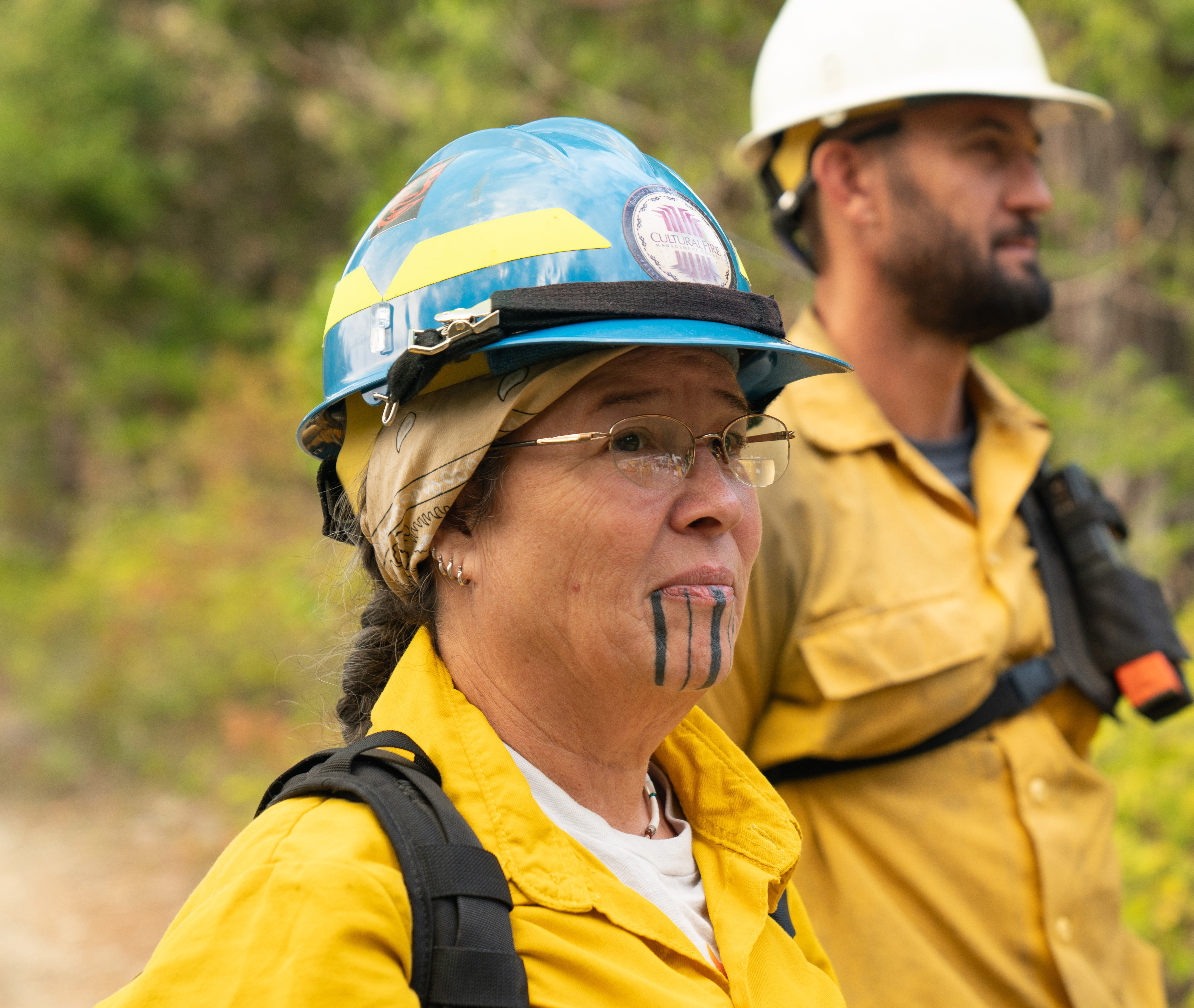 Women in yellow fire gear and blue hard hat.