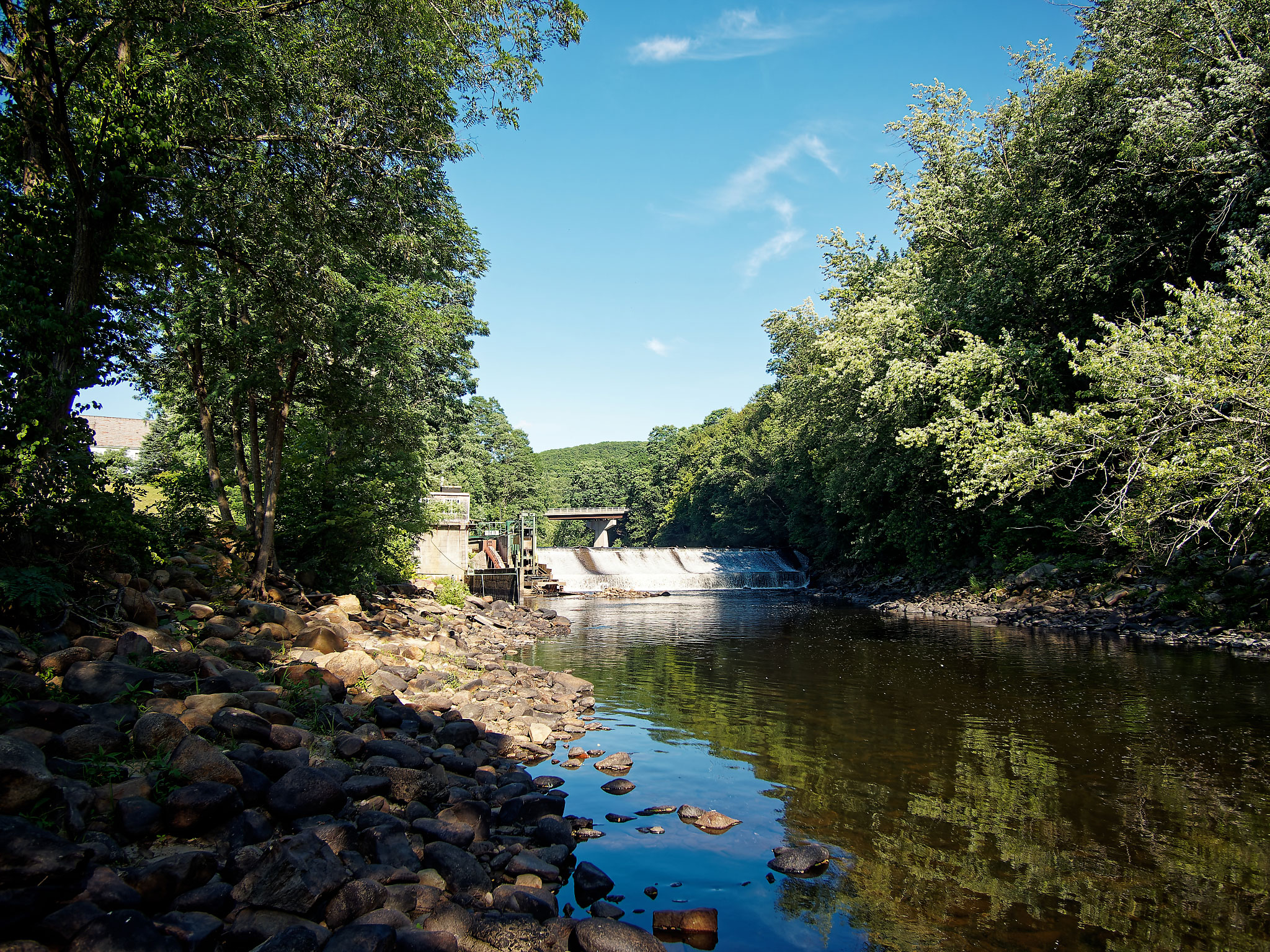Water flows over a dam into a river.