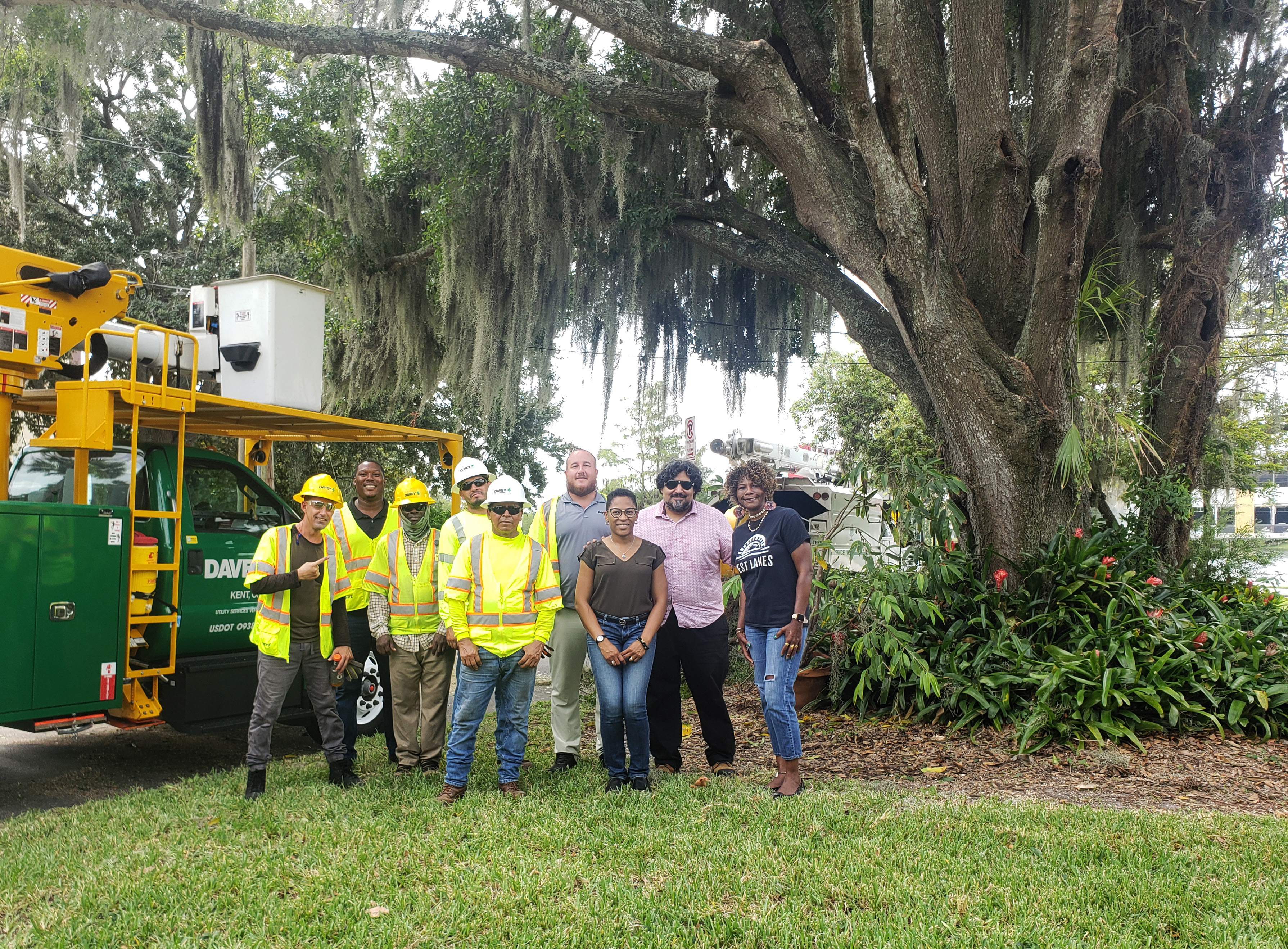 A group of people pose together under a tree.