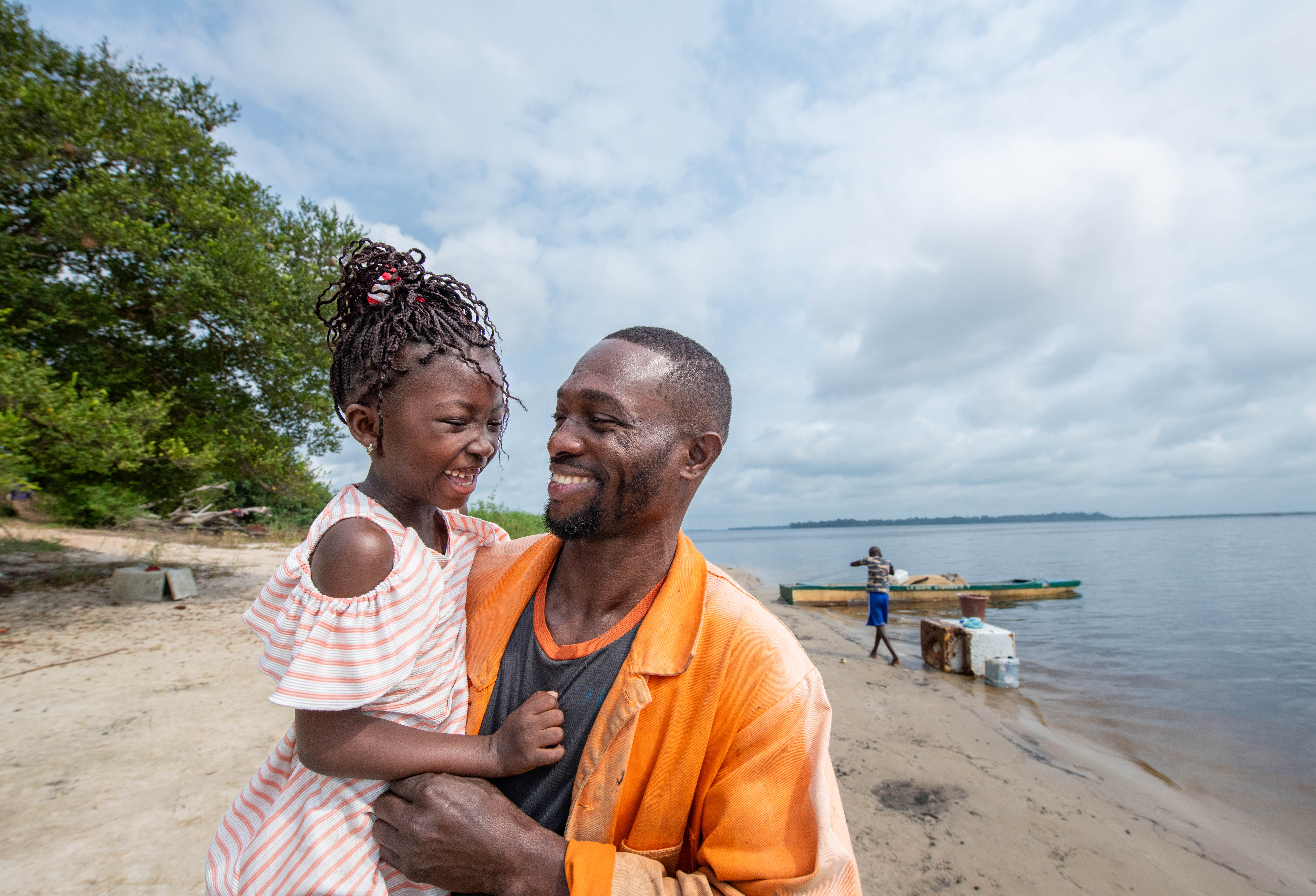 Annael Prince Reteno holding his niece Kensy on the shore of Lake Anengué in Gabon.