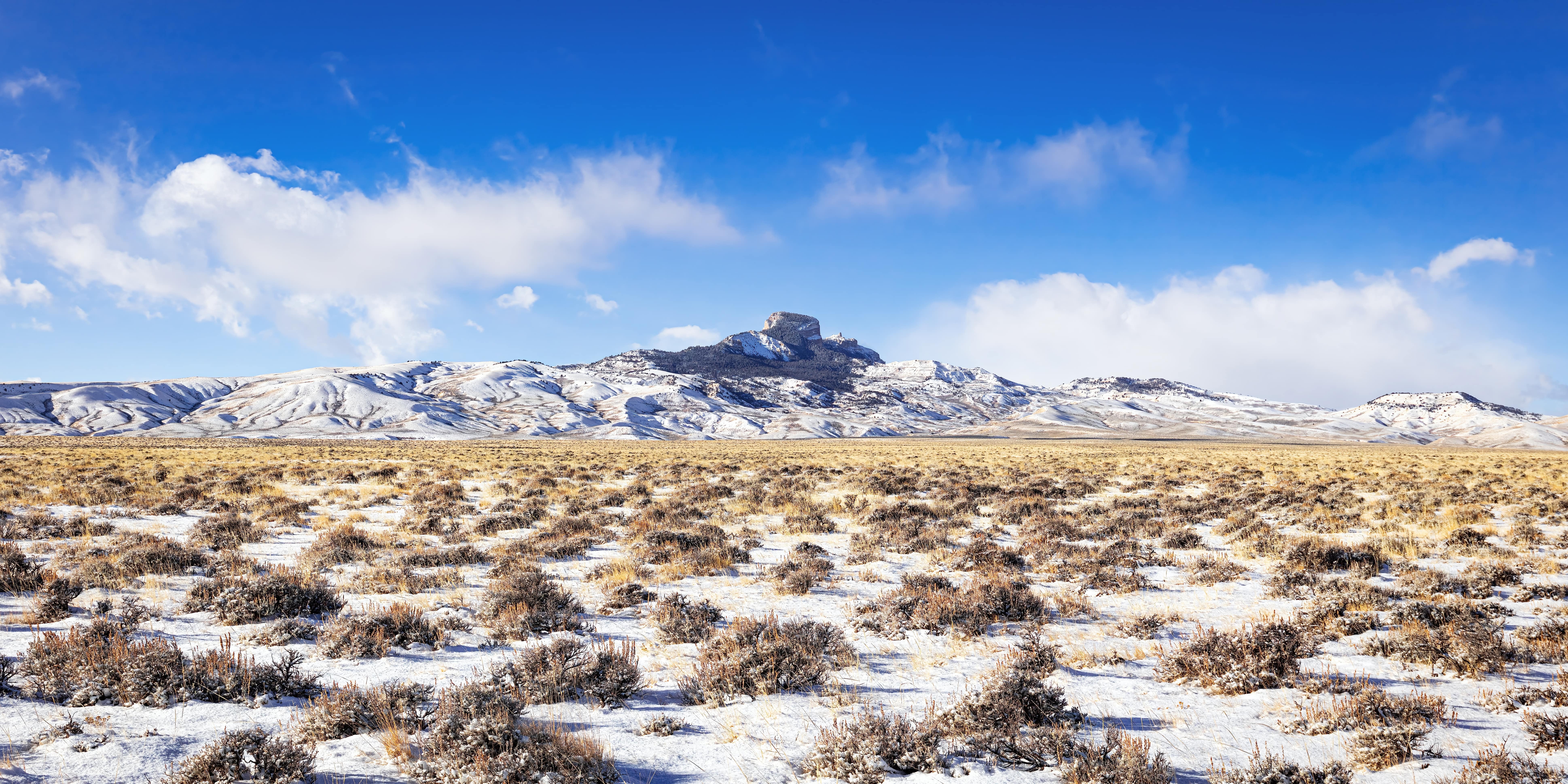 A large mountain emerges from a vast, snowy landscape.