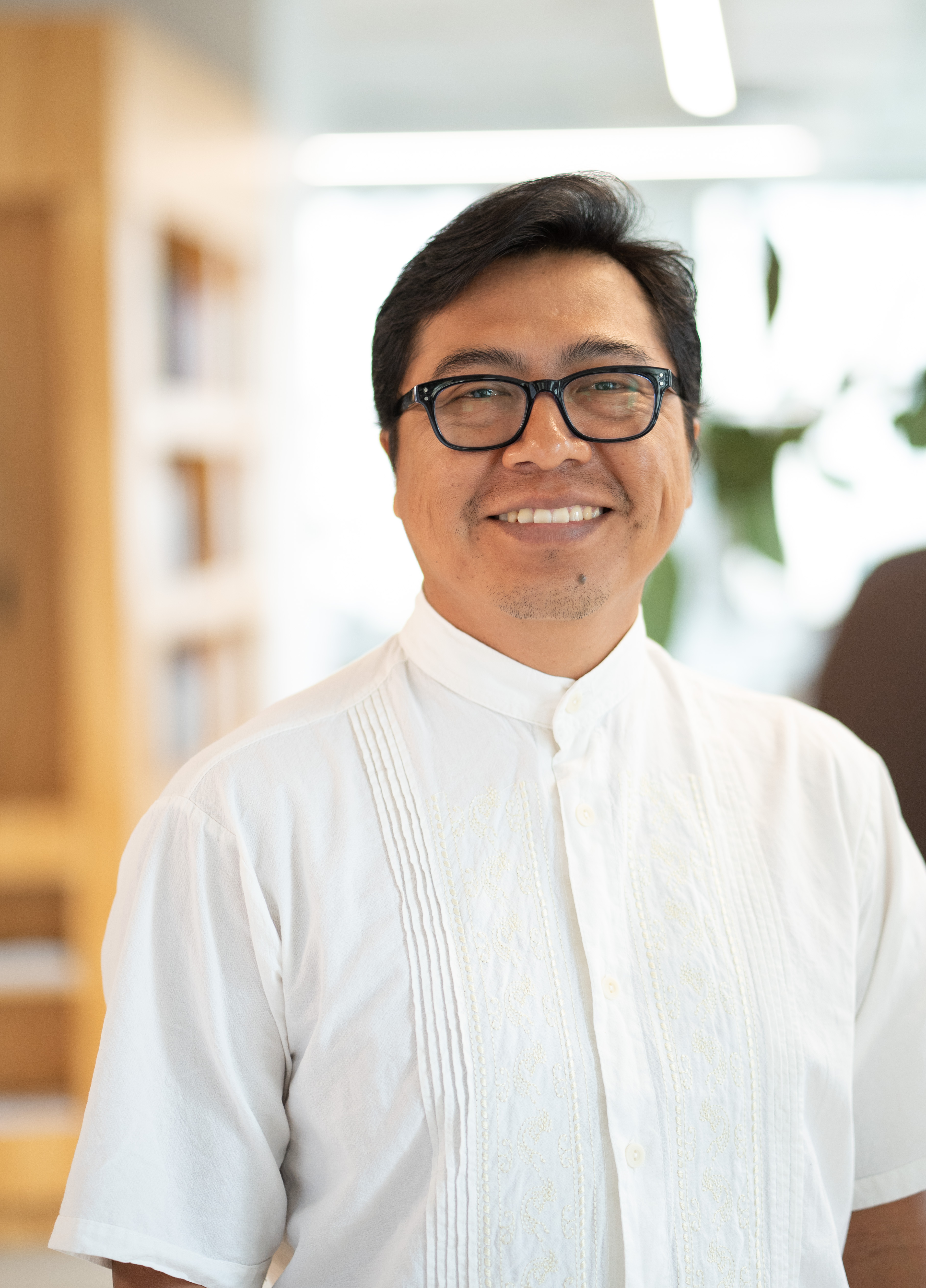 A portrait of a man wearing black-rimmed glasses.