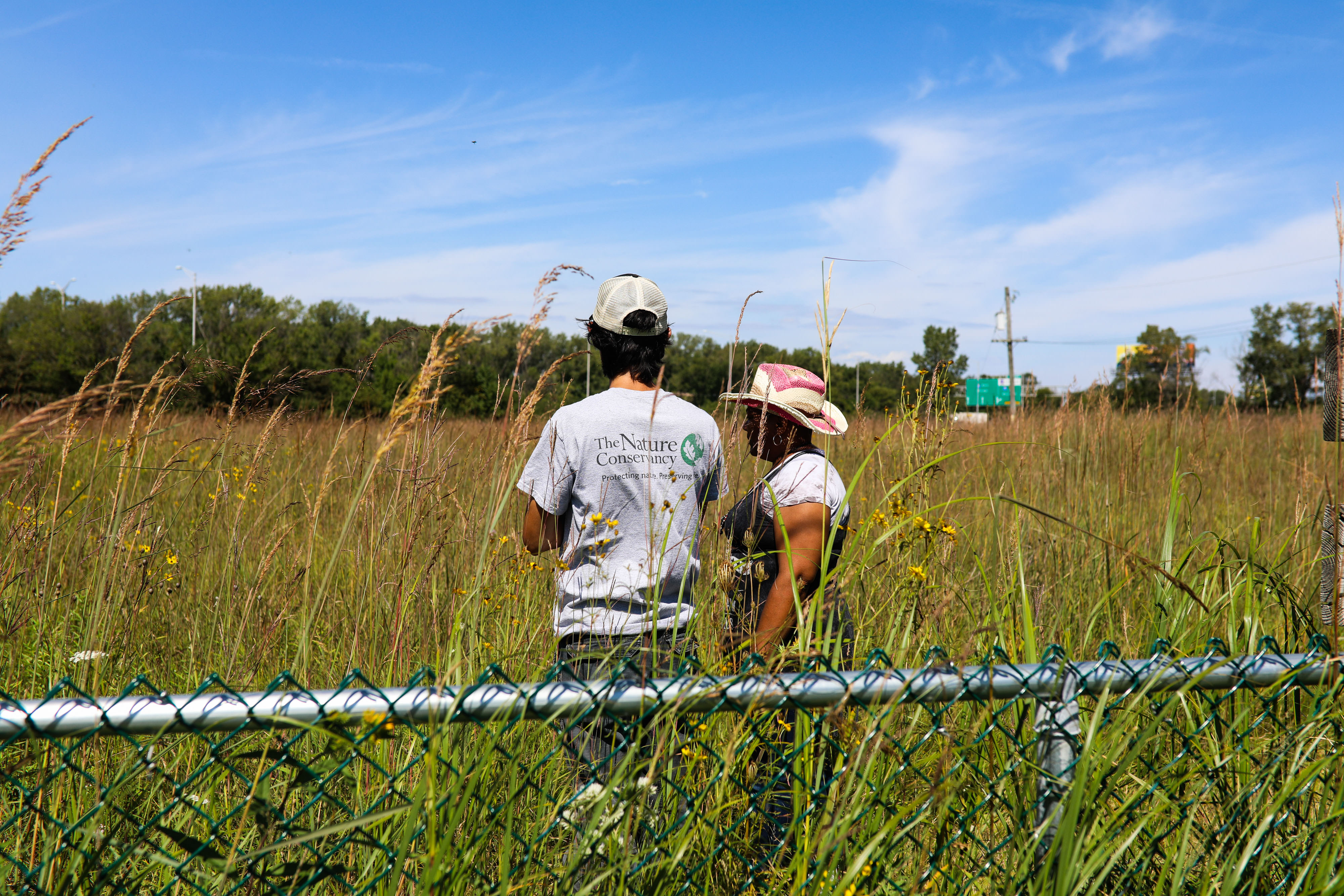 Two people standing in a field of waist high plants.