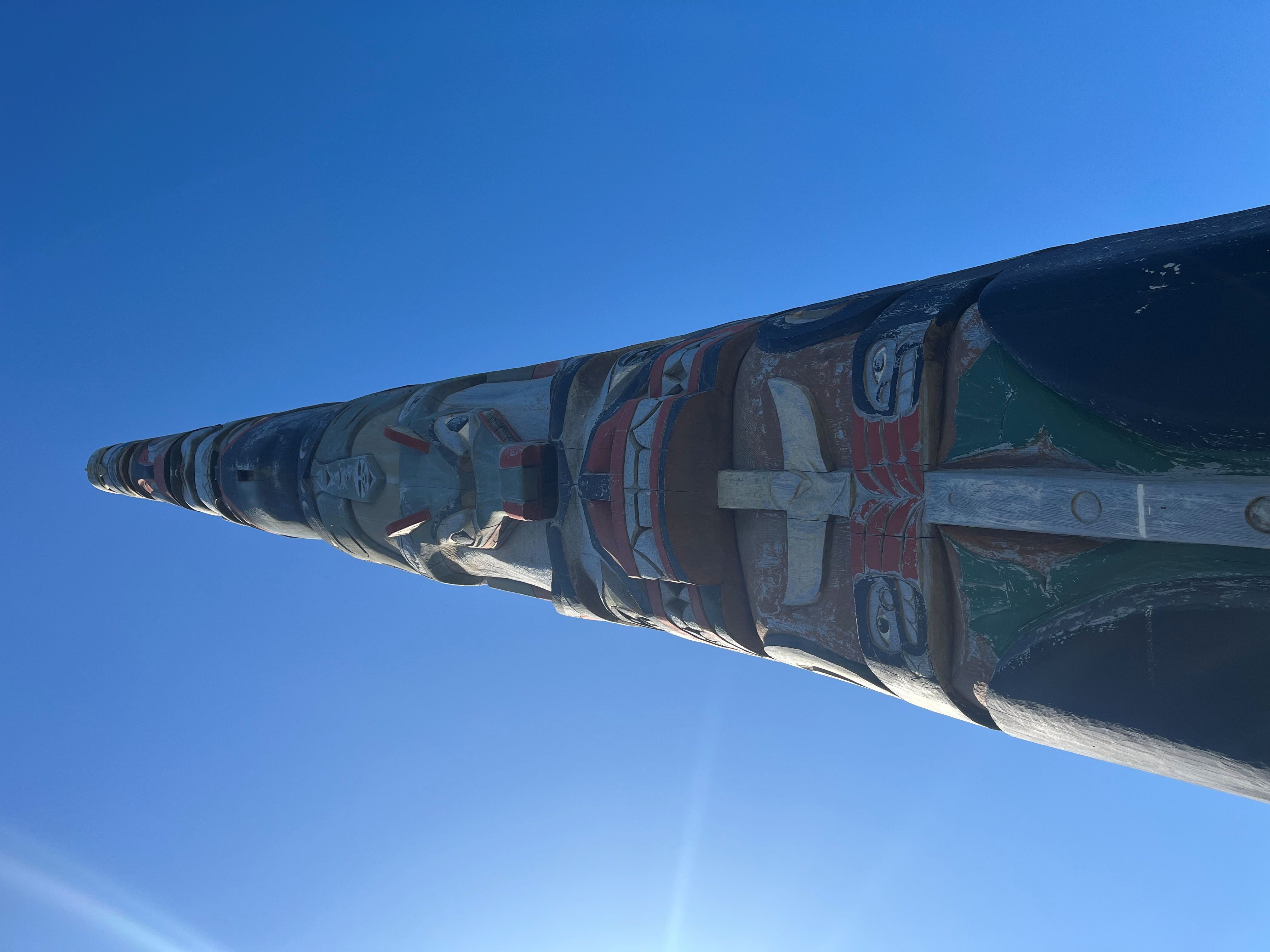 Bottom-up view of a Quinault Indian Nation red cedar totem pole on a cloudless, sunny day.