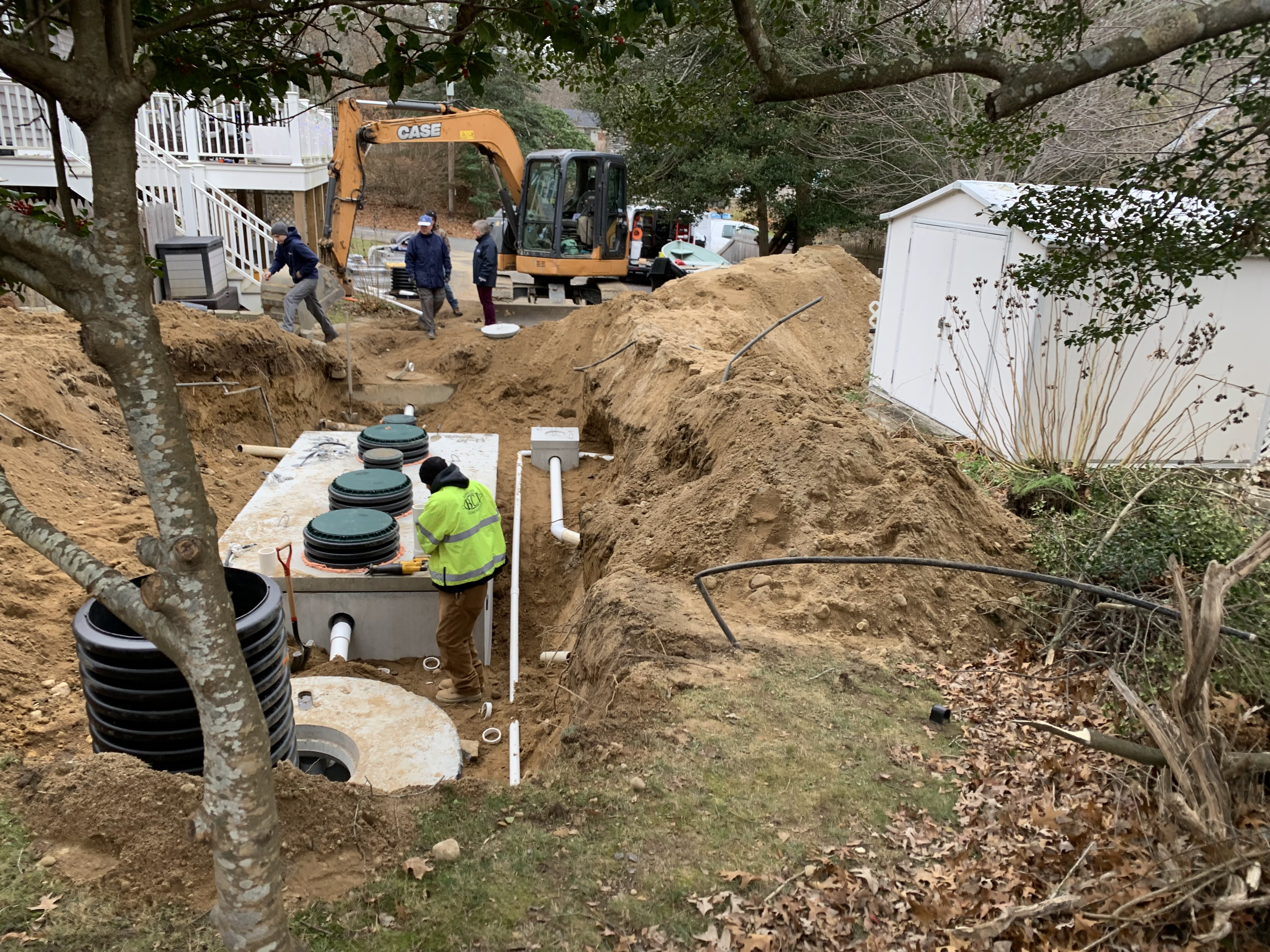 A concrete septic system sits in a hole in a backyard.