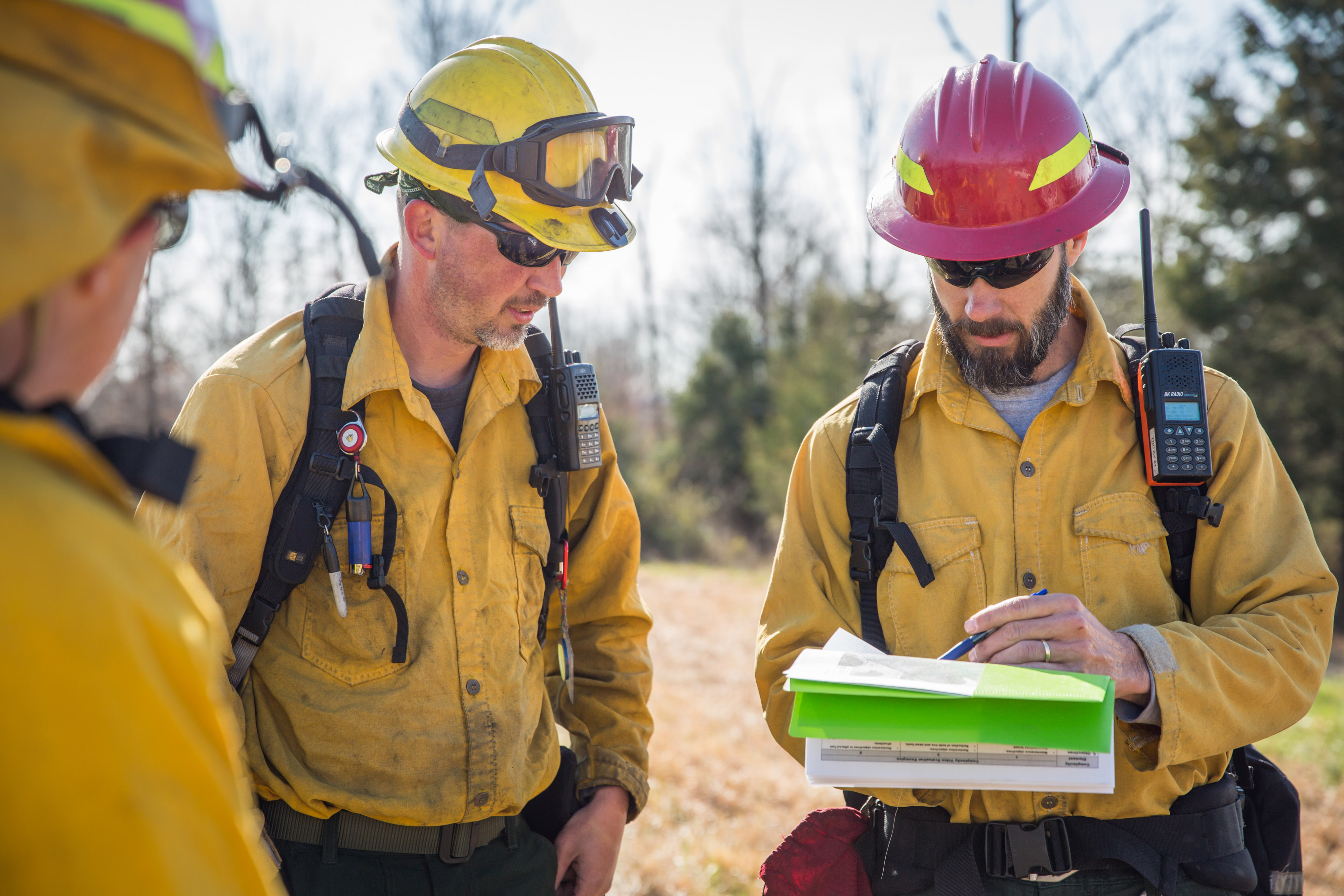 Burn boss discusses burn plan with crew in safety gear.