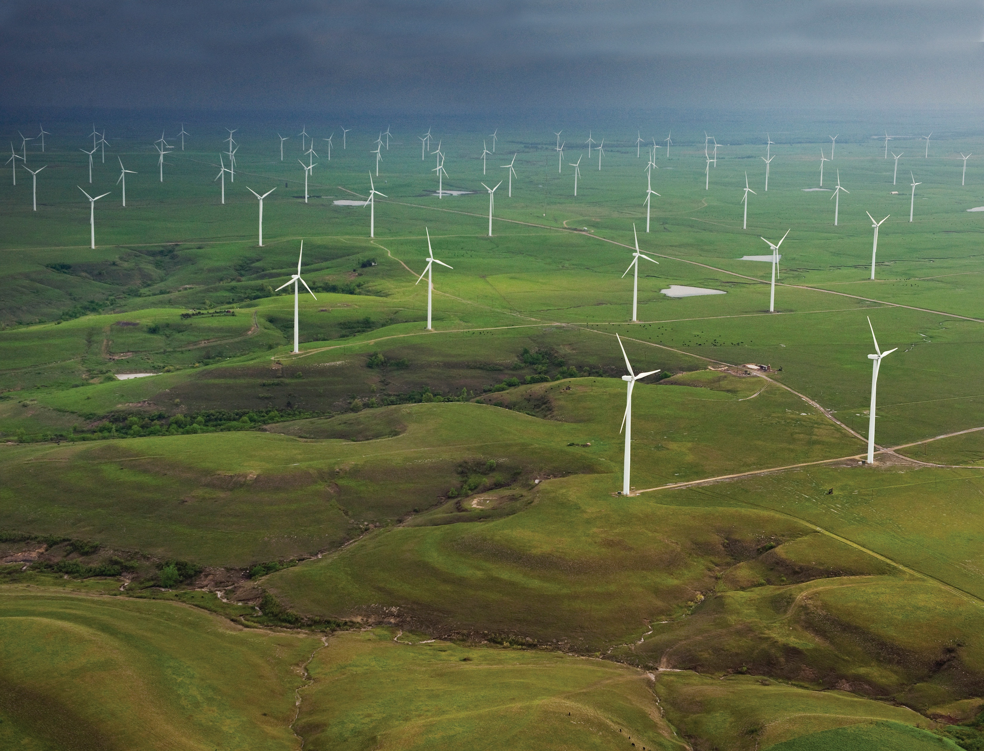 An aerial shot of wind turbines in a flat grassland landscape. 