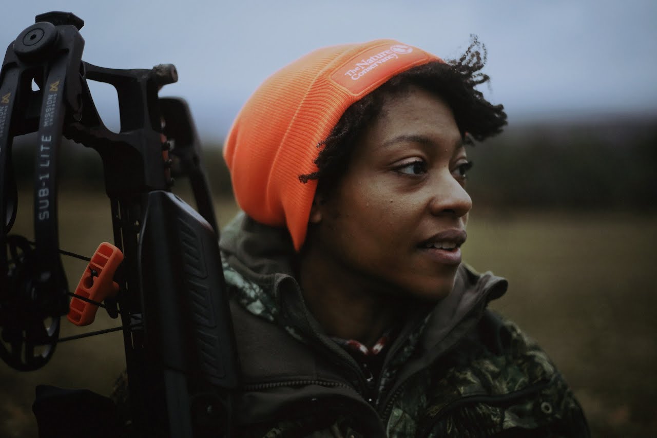 A photo of Liana George wearing a blaze orange beanie.