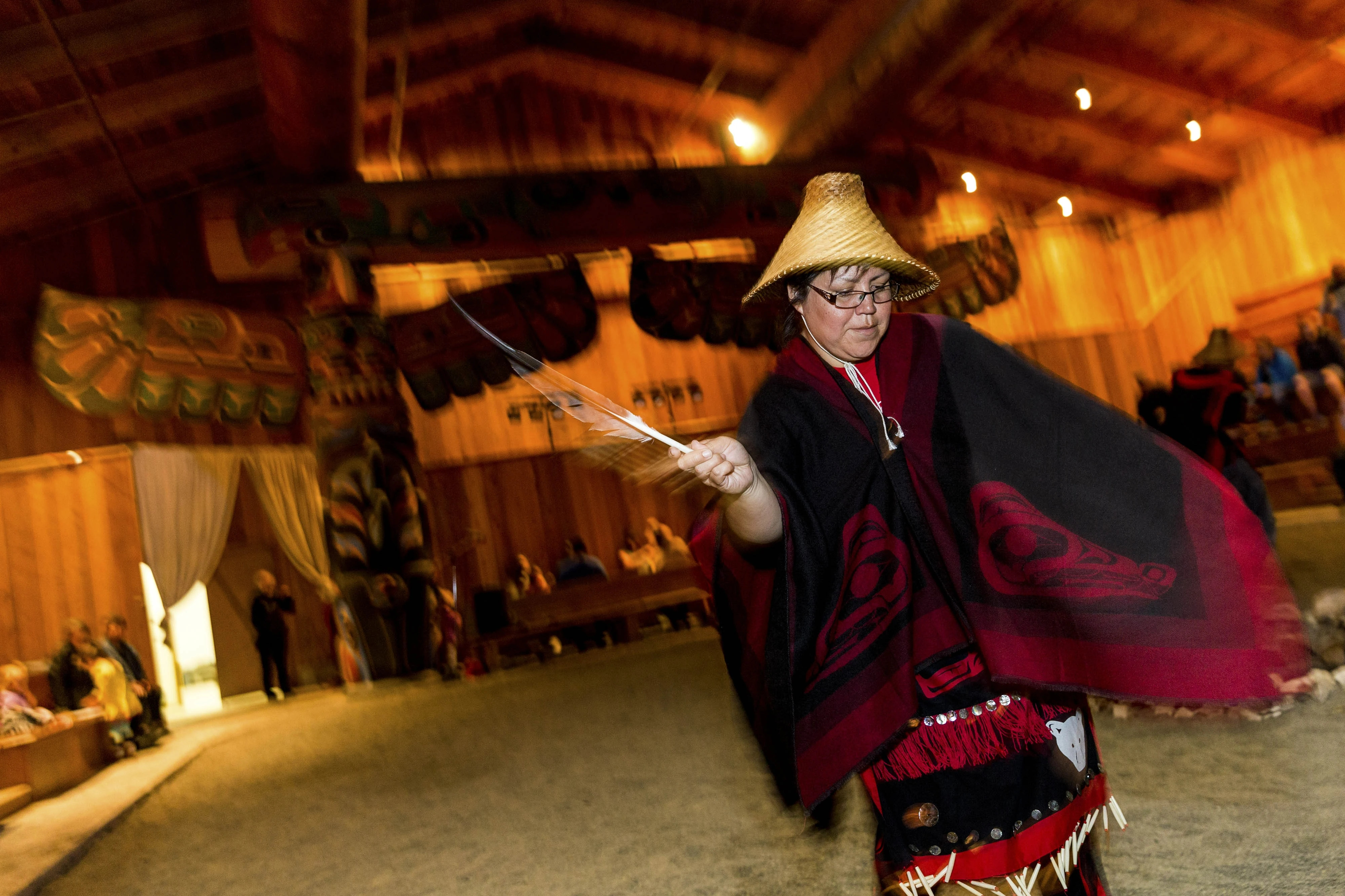 an indigenous woman performs a traditional dance in the Kitasoo/Xai’xais Big House in the Great Bear region of British Columbia.