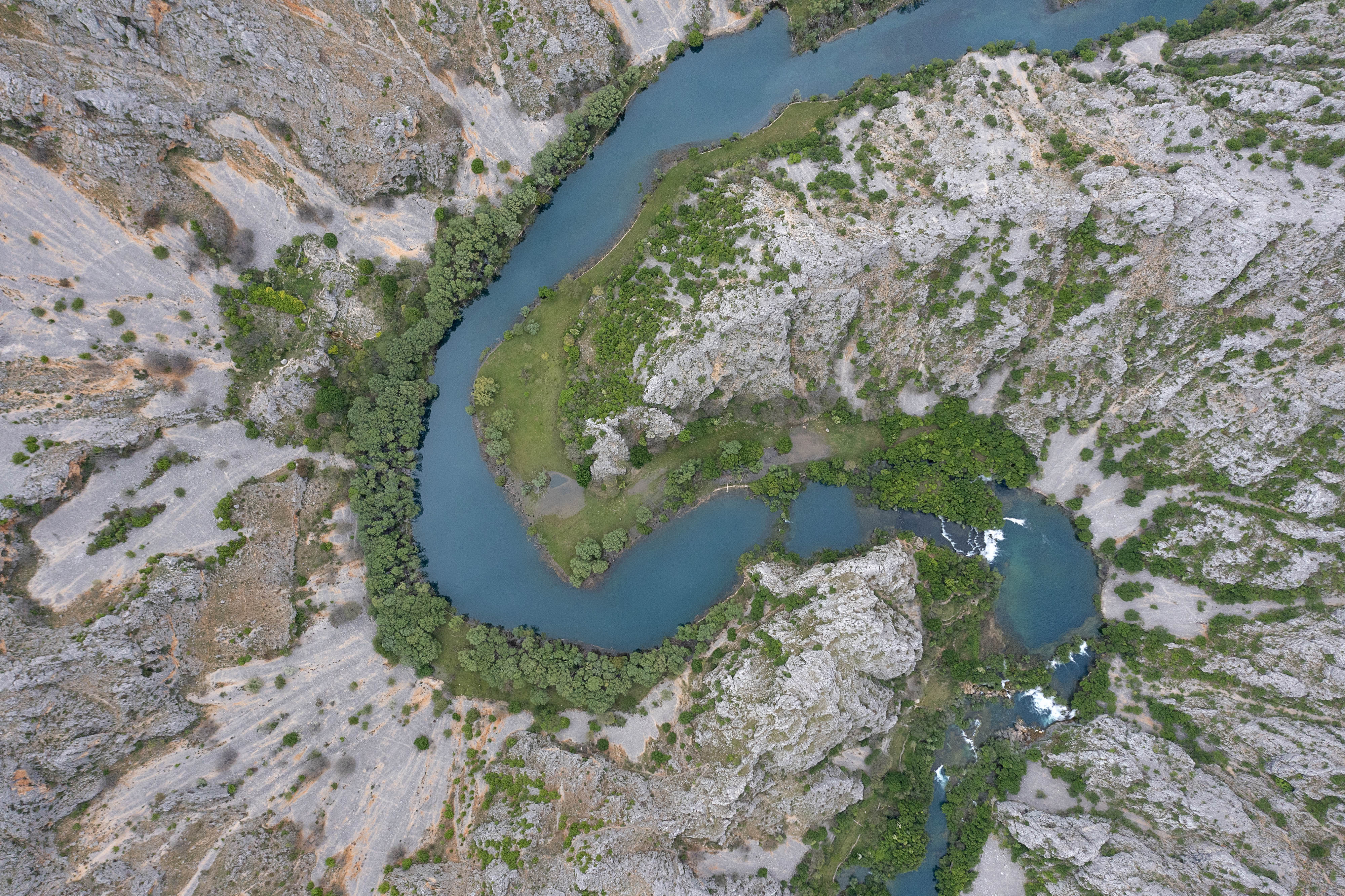 An aerial view of a river shows it following a bend.