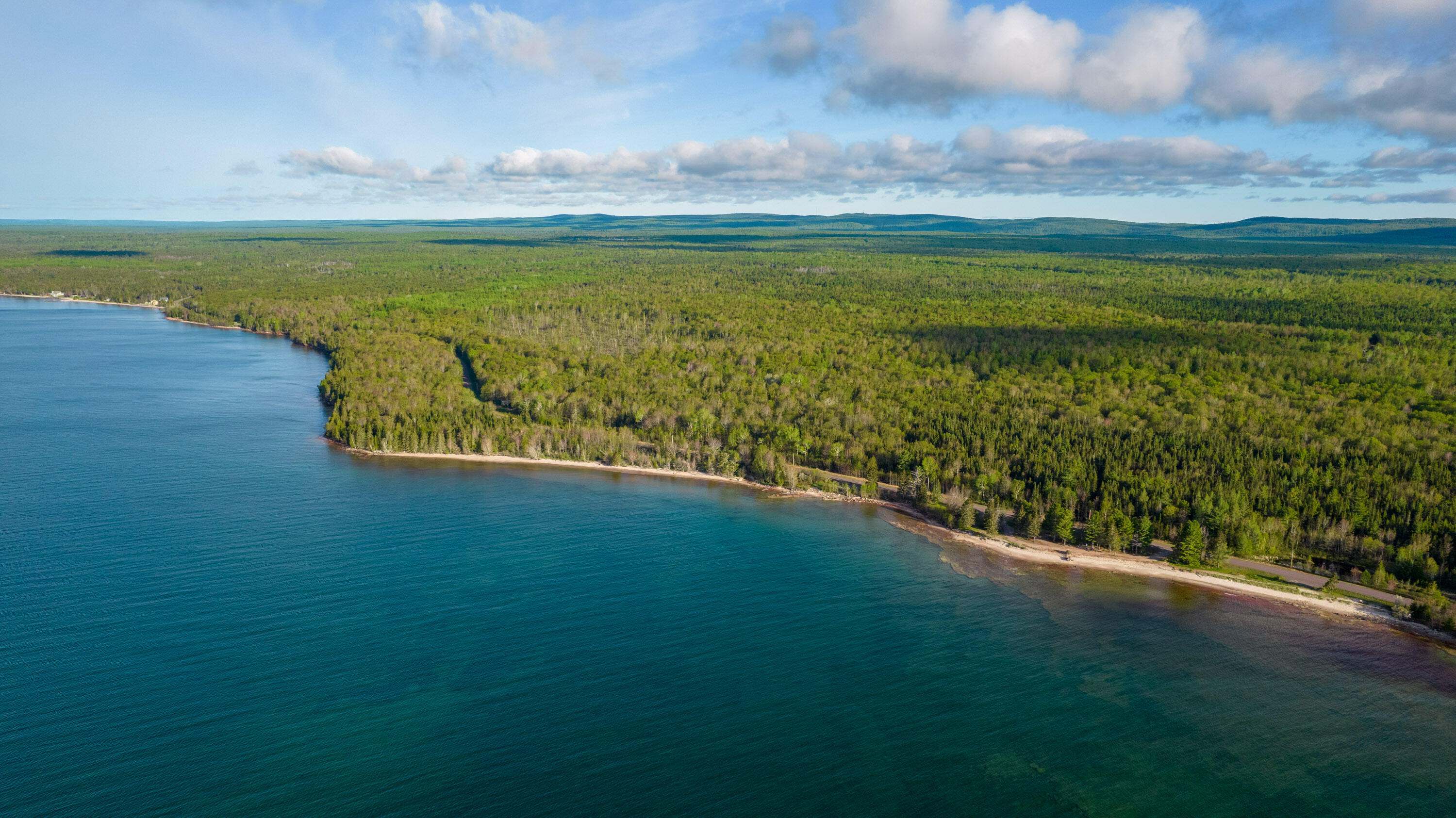 The Little Betsy Shoreline in the Keweenaw Peninsula. The water of Lake Superior is blue and the sky is clear. 
