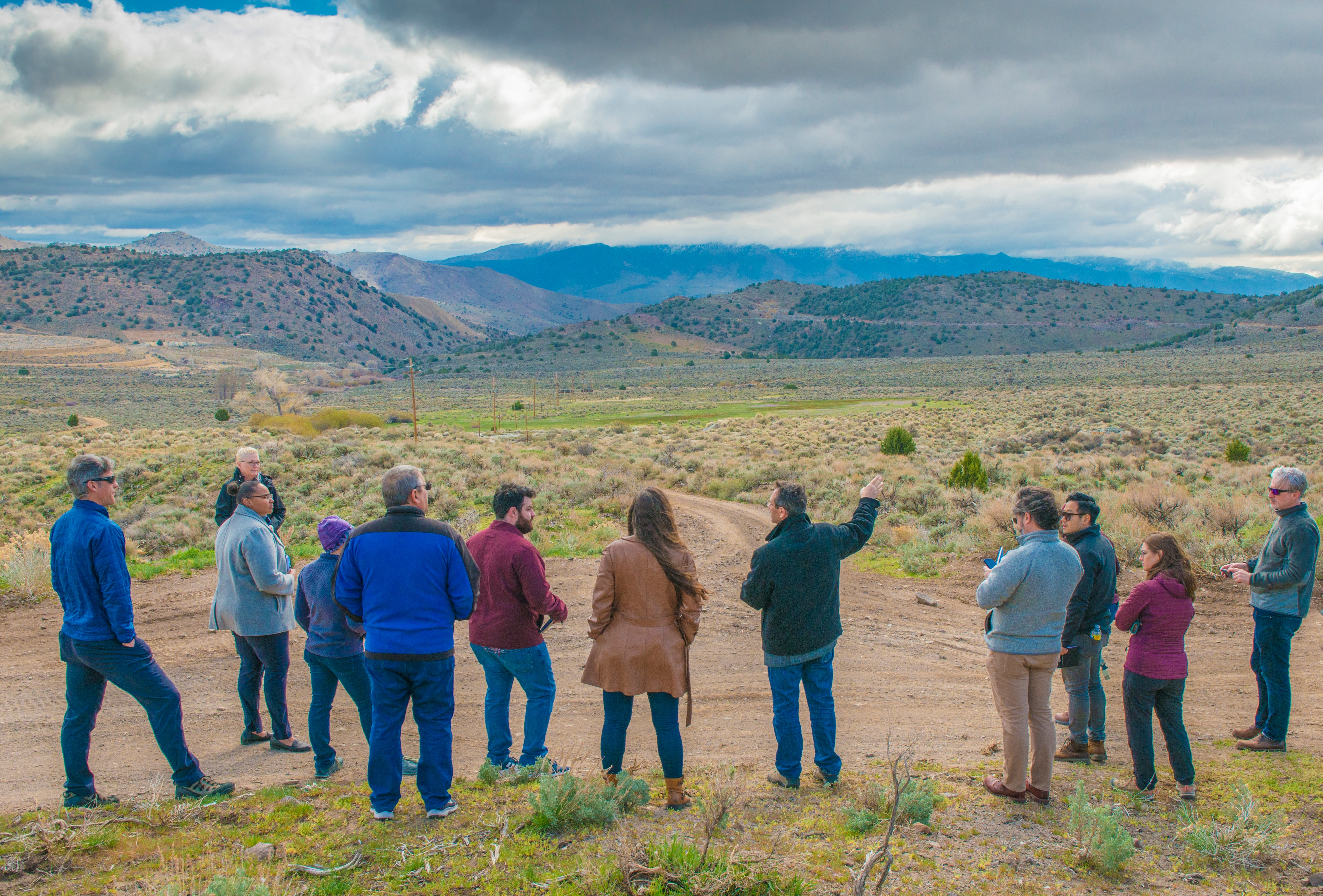 A group of people overlooking a field of grasslands and rolling hills.