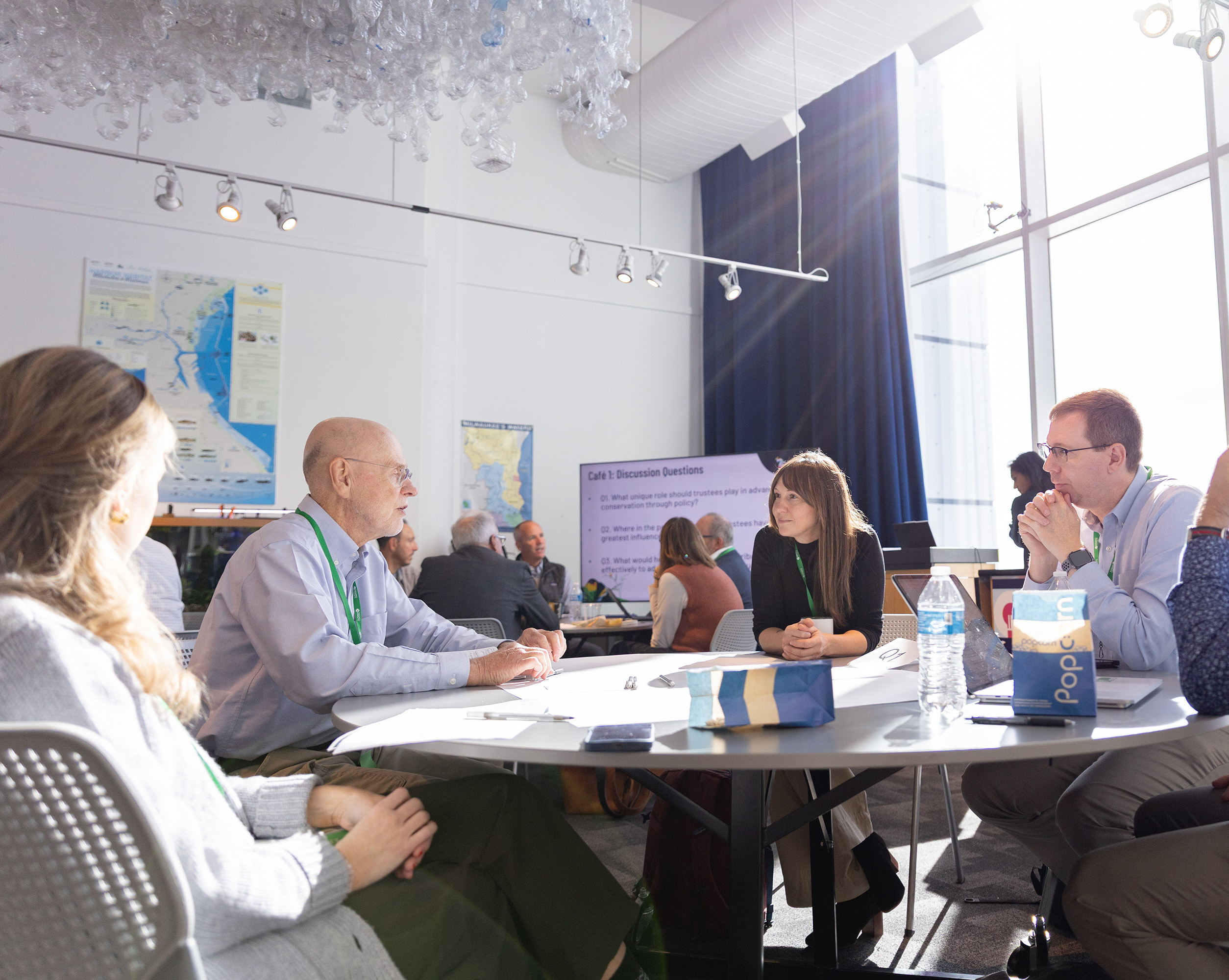 People dressed in business attired sit and talk around a table.