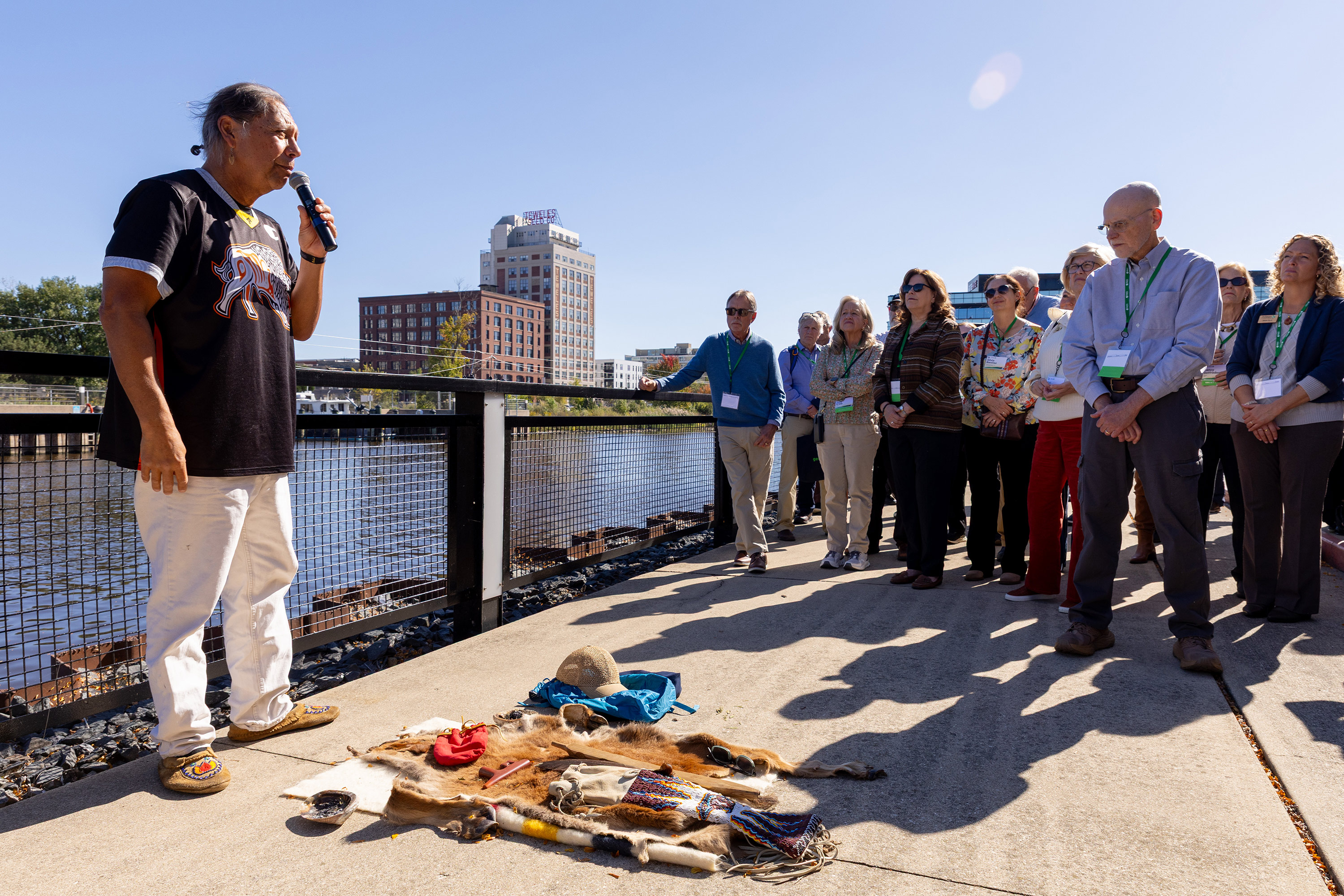 A man holding a microphone speaks to people gathered outside.