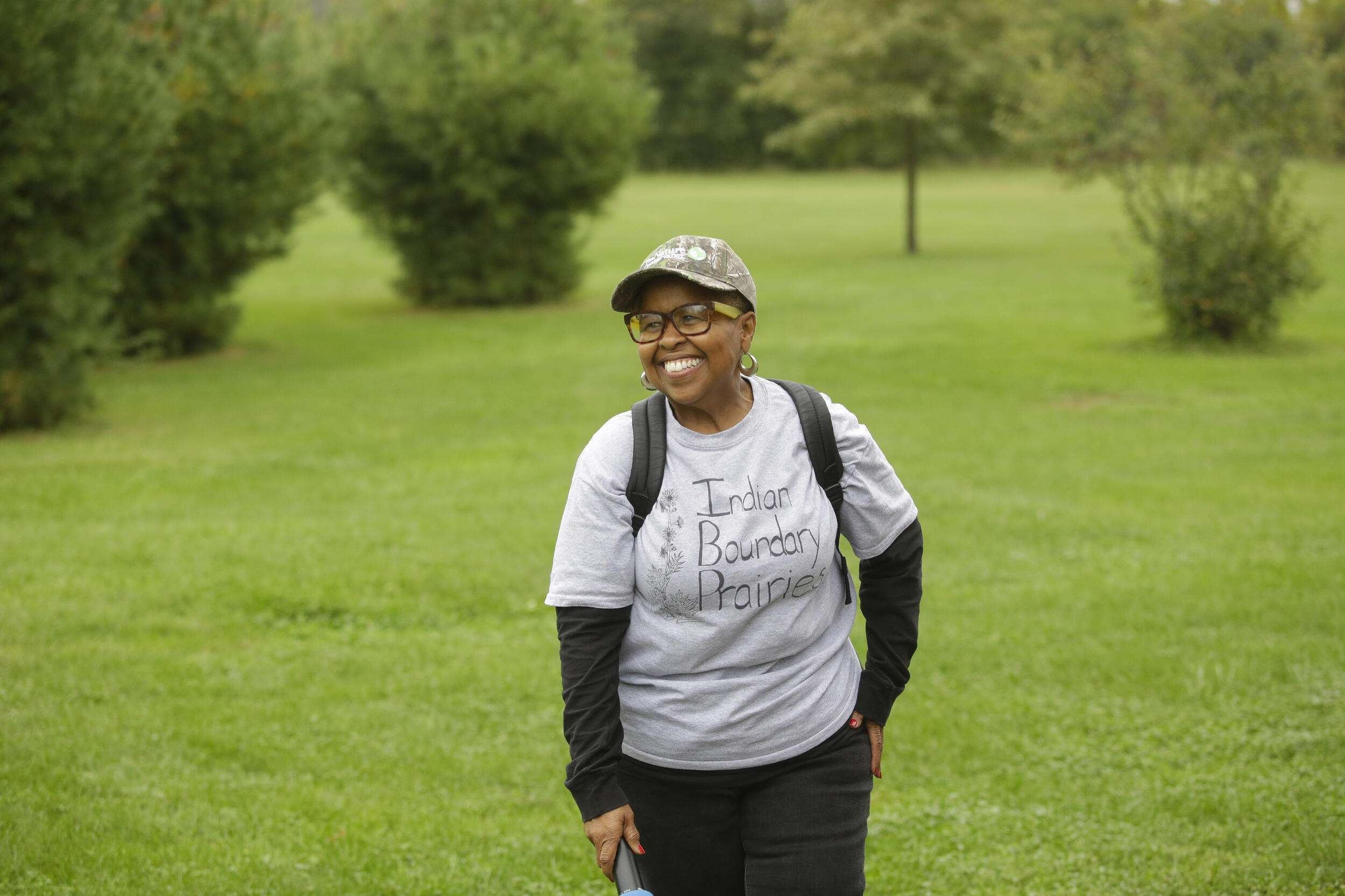 A woman wearing a ball cap standing in a meadow. 