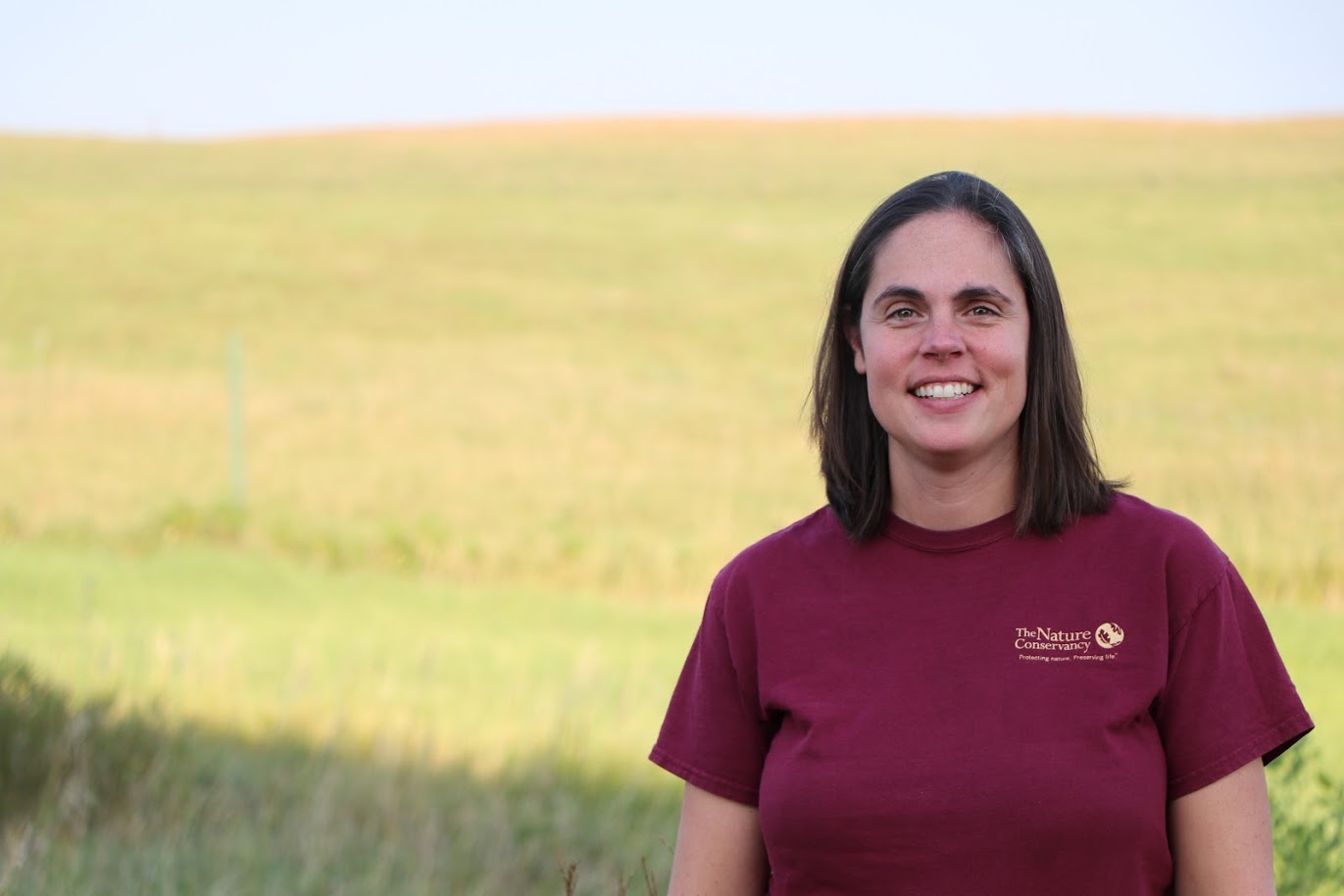 A woman in standing outside in a prairie. 