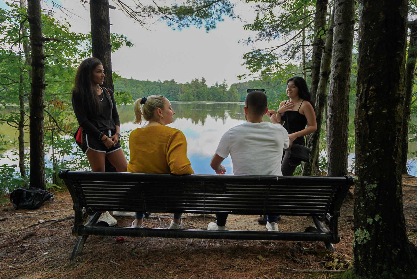 Four people around a bench next to a river.