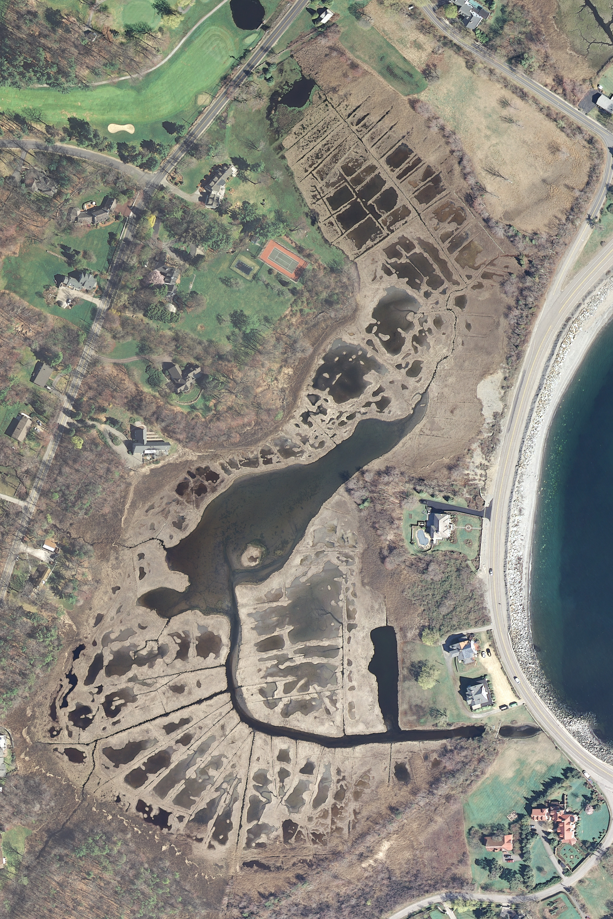 An aerial view of flooded saltmarsh with houses nearby.