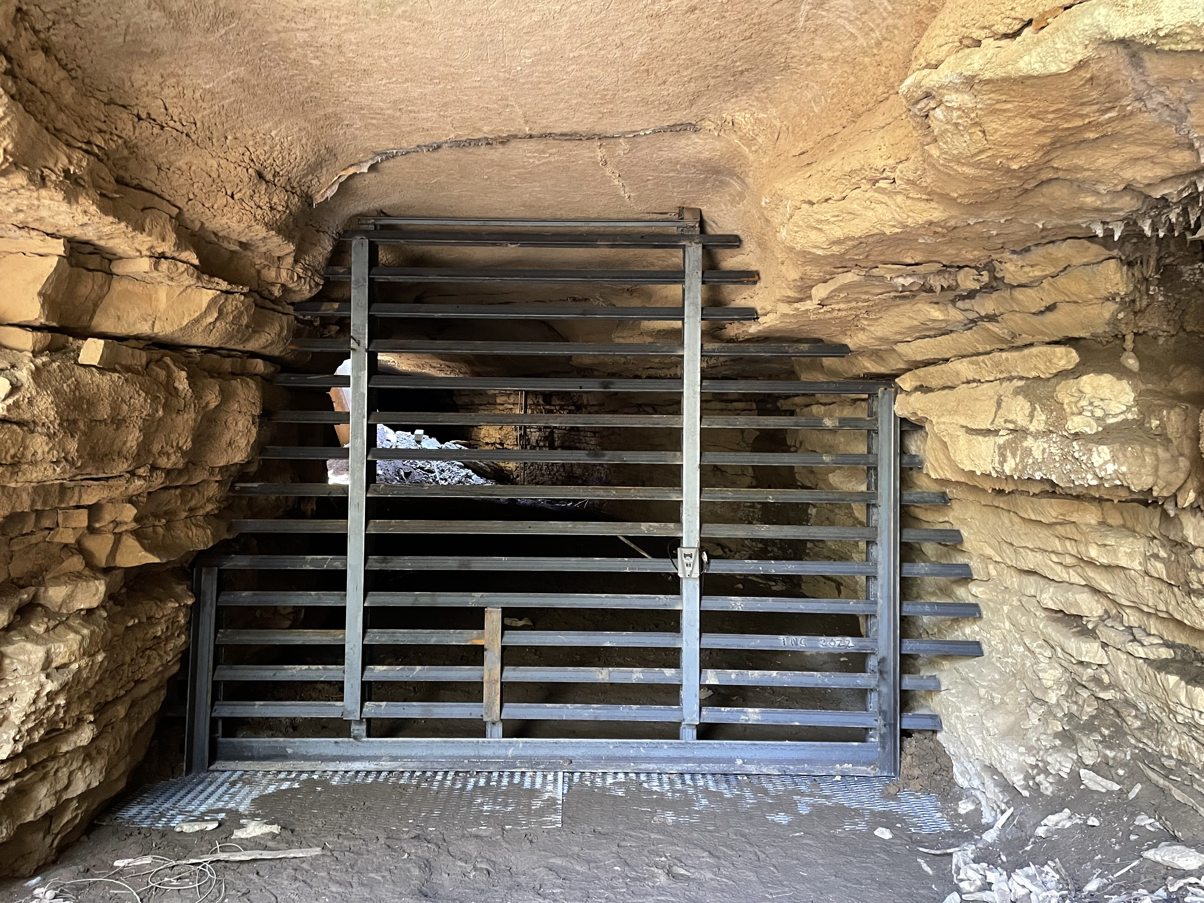 A slatted metal gate built into a cave entrance.
